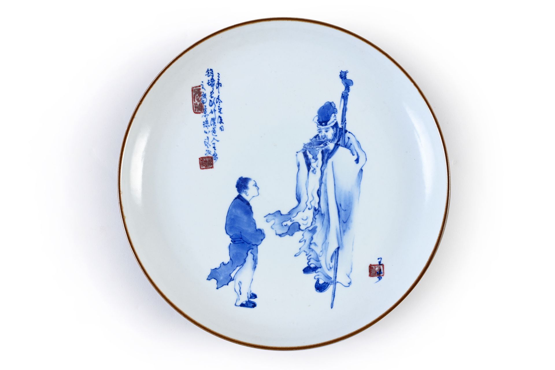 Attribué à WANG BU (1896 - 1968) 优雅的瓷盘，白底钴蓝装饰，仙人与小孩相伴，边框施棕色釉，艺术家签名，背面有诗和标记。
直径：2&hellip;