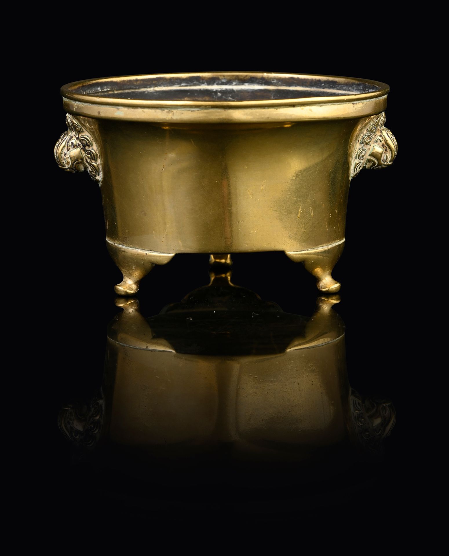 CHINE, XVIIe siècle 一个小型的铜制香水炉，圆柱形的炉身安放在三个弯形的脚上，两边是两个狮子面具形式的把手。底下刻有一个六字的宣德款。
高：6&hellip;