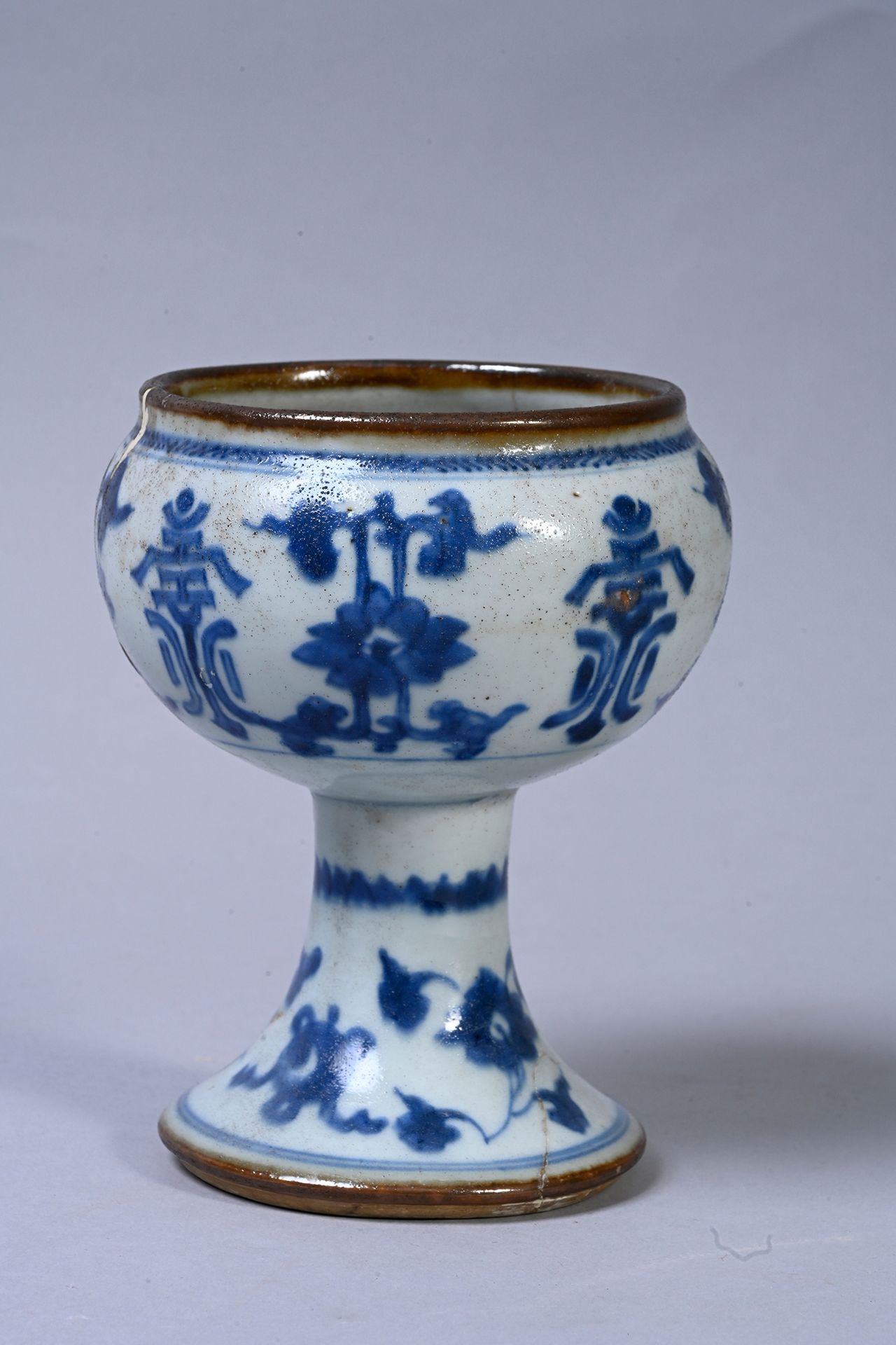 CHINE, XVIIe siècle 一件青花瓷座碗，有卷轴、花朵和长寿的标志。颈部和底座的边缘经过烧制。底部未上釉。
高度：13,8厘米
修补和修复