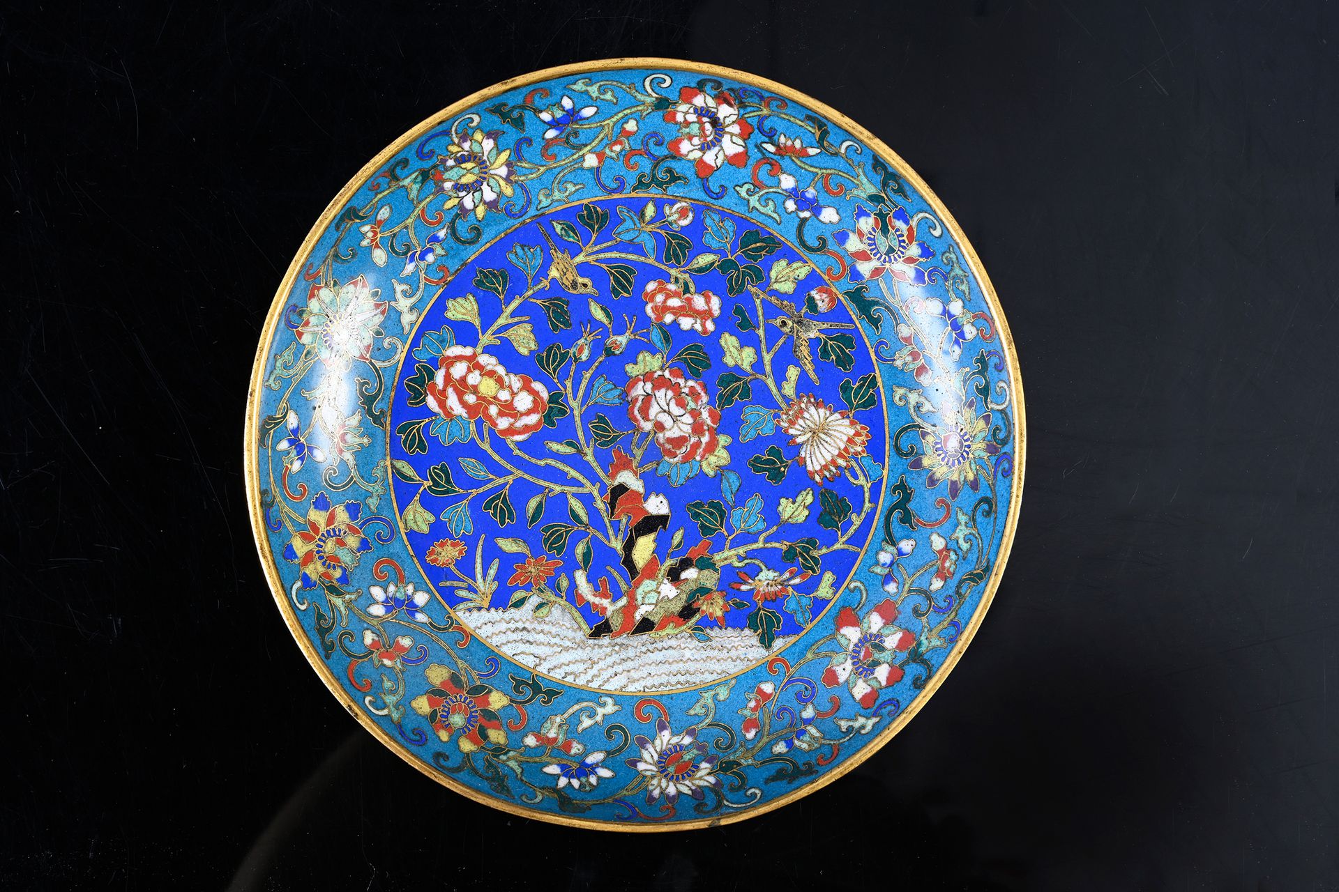 CHINE, XIXe siècle 景泰蓝盘子
中央图案为蓝底的牡丹花、菊花和鸟，边饰为绿松石底的莲花卷，外壁重复装饰。
直径：19厘米