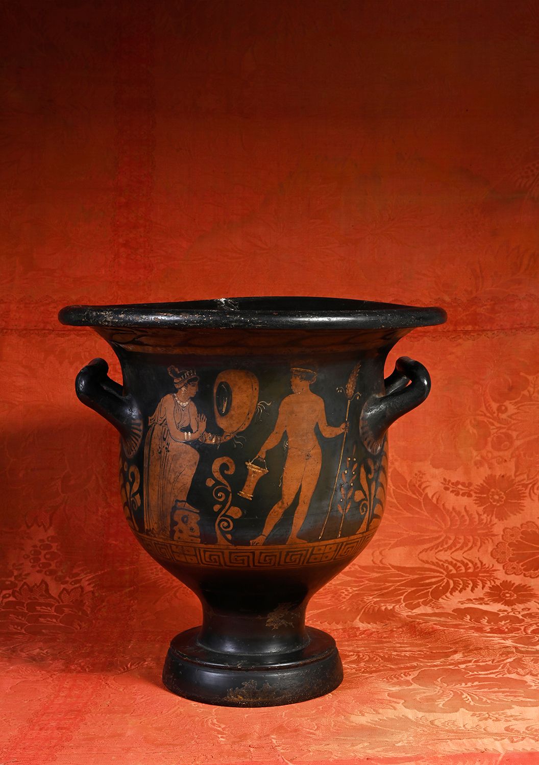 Null 红色图案的钟形水壶，一面装饰着一个年轻女子手持Tympanon的场景，面对一个手持胸针和situla的裸体萨提尔。B面表现的是一个石碑两边的两个正在对&hellip;