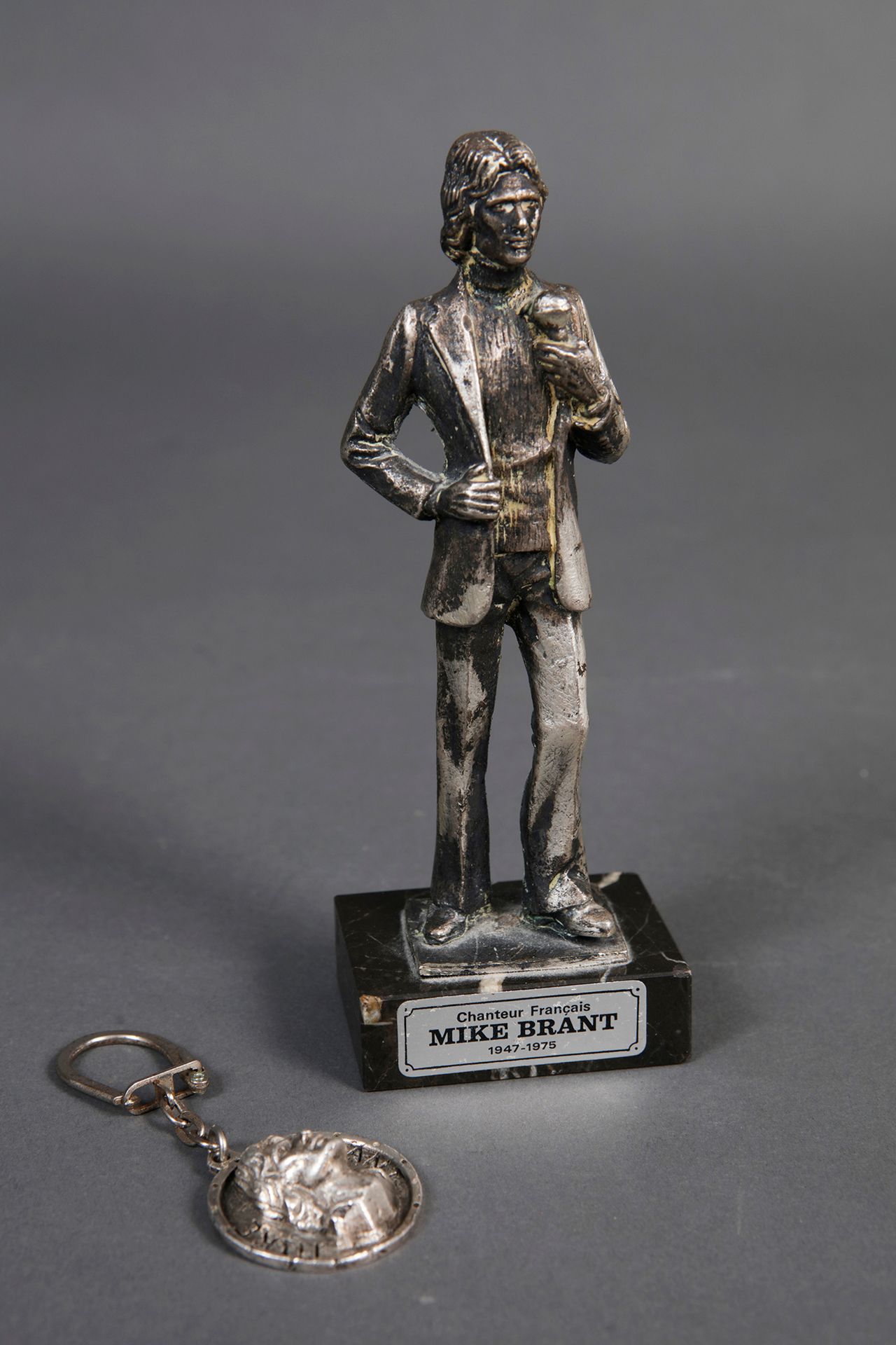 Null 迈克-布兰特
1个金属的歌手小雕像，大理石底座，1978年和他去世三周年之际编辑的。高16.3厘米。附有一个带有迈克-布兰特脸部的金属钥匙圈。
状况良&hellip;