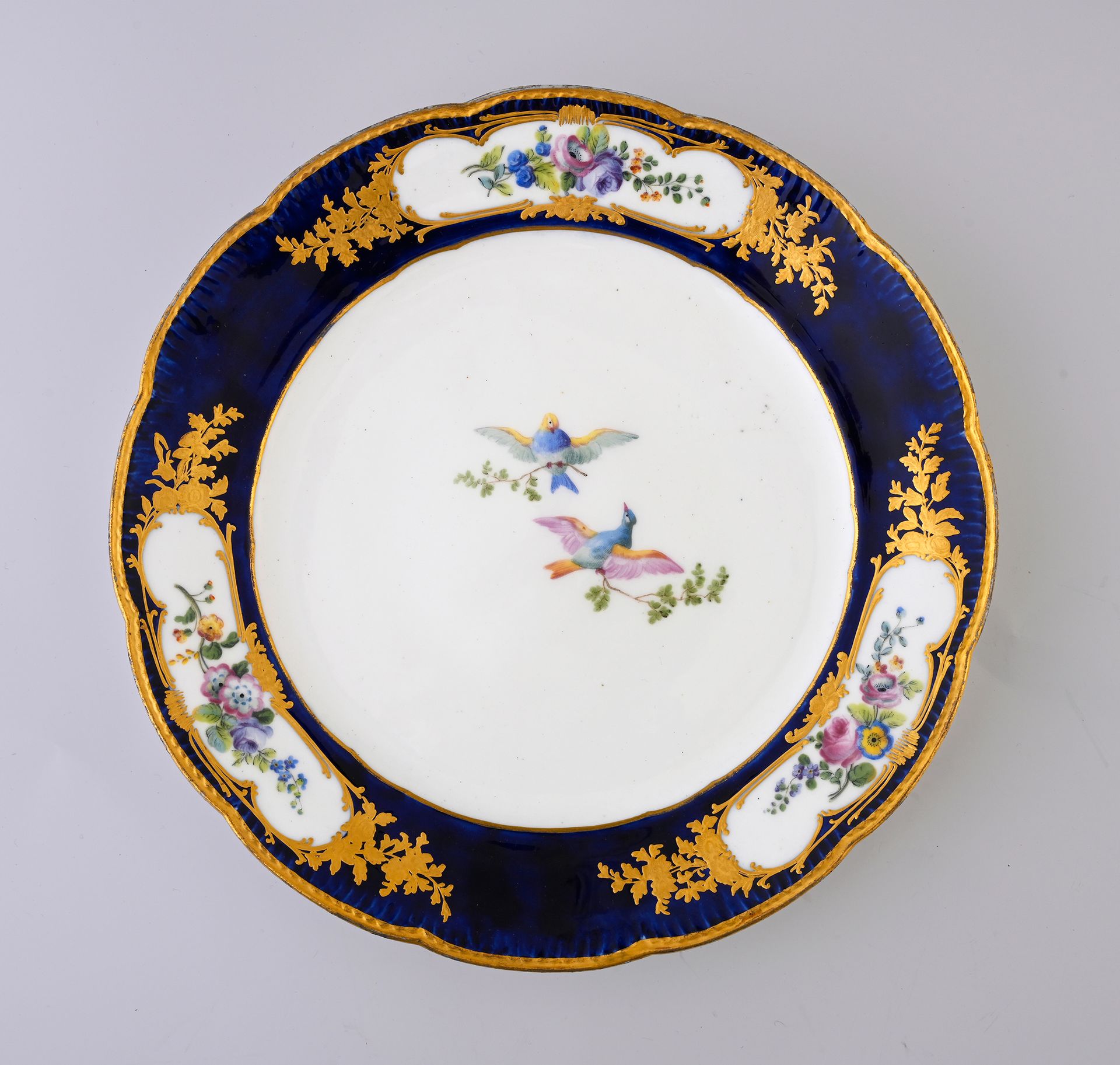 Null 18世纪塞夫勒的一个带装饰品的瓷盘
蓝色标记有两个交错的L，日期字母F，画家标记可能是Tollot的标记
带有多色装饰，中间是两只飞翔的鸟，翅膀上的花&hellip;