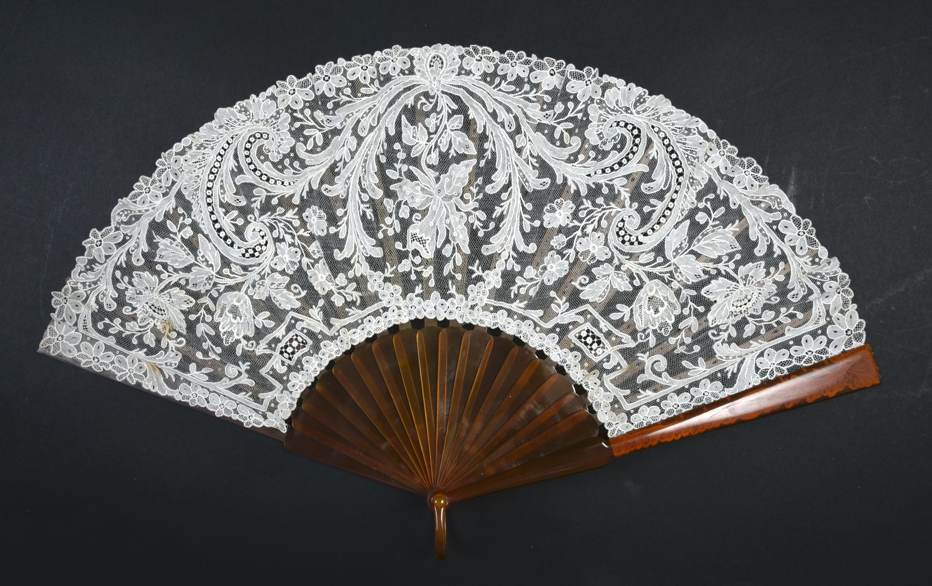 Null 兰花，欧洲，约1900年 
折叠的扇子，叶子是白色的针状花边，纱布缝制，中间装饰着一朵兰花，被卷轴和玫瑰花框住。各种模式。模仿金黄色玳瑁的安装。扣子。&hellip;