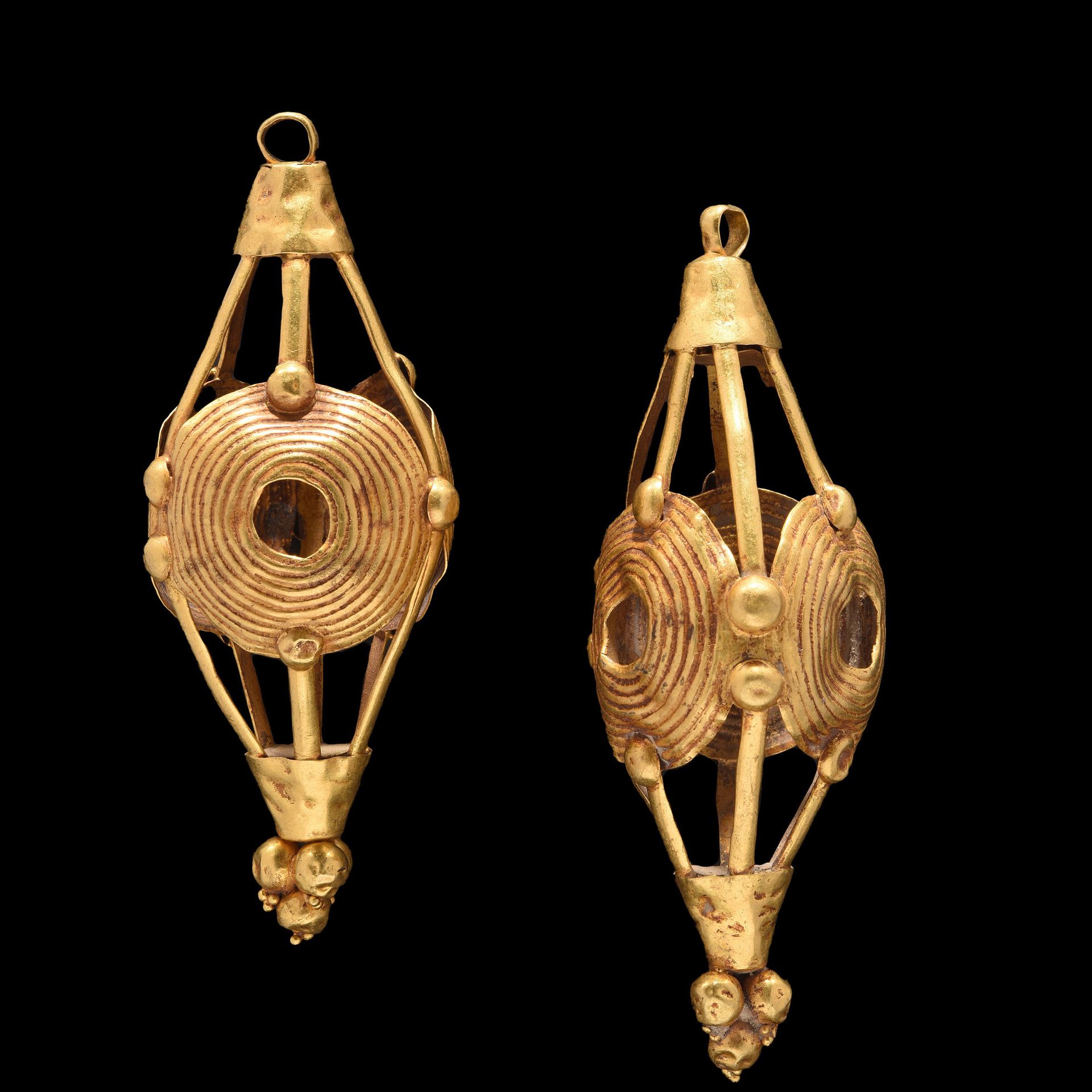 Null 耳环一对

东地中海晚期或更晚。

由镀金铜合金制成，呈镂空菱形，由条状和盘状组成的编织，上面有同心圆的图案装饰。

顶端装饰有3个空心球体。高8厘米&hellip;