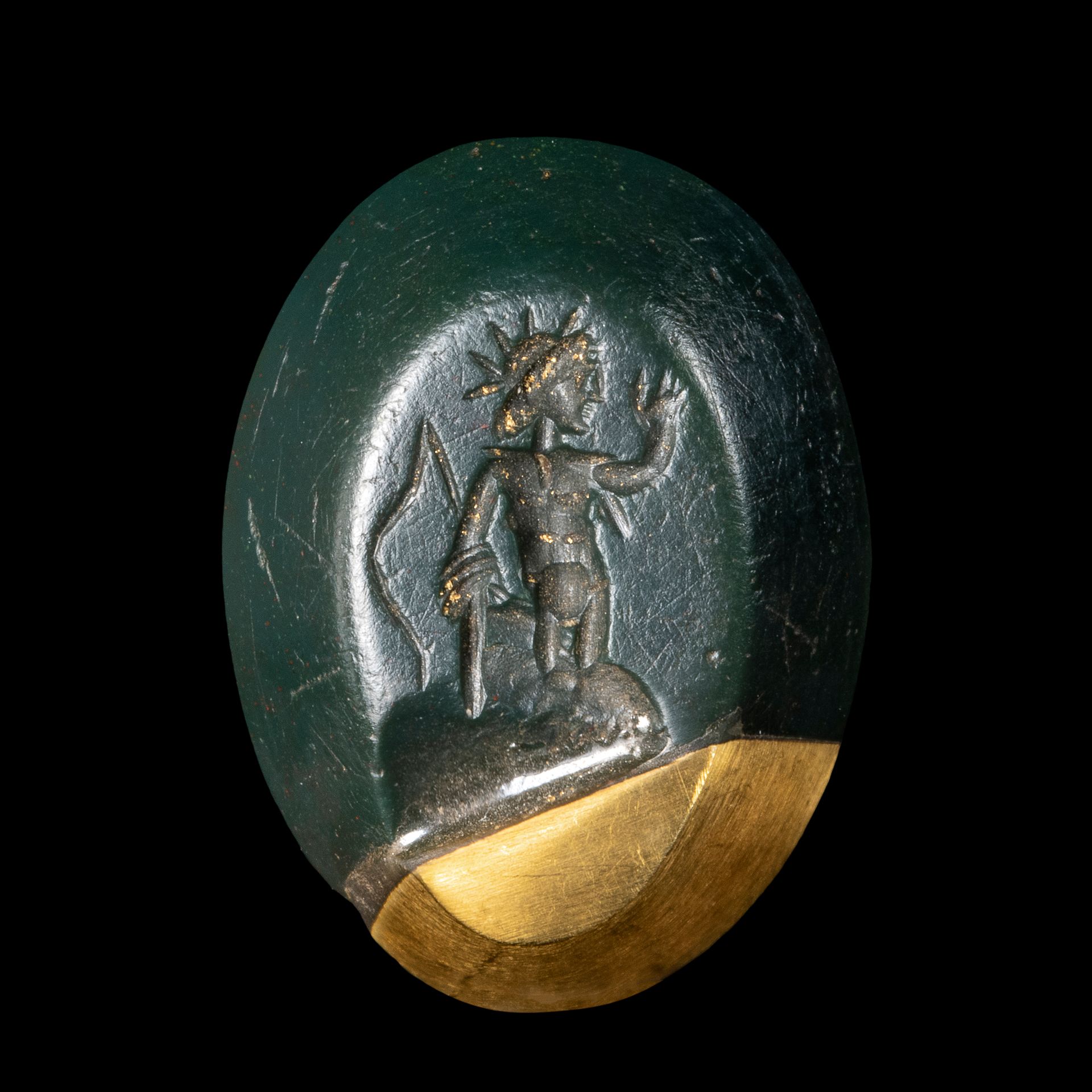 Null 可知的凹版画
在血绿色碧玉上，显示赫利俄斯神站在左边。
有缺口，并与黄金结合。
13 x 17 x 4 mm
罗马艺术，2-3世纪

一件罗马绿碧玉凹&hellip;