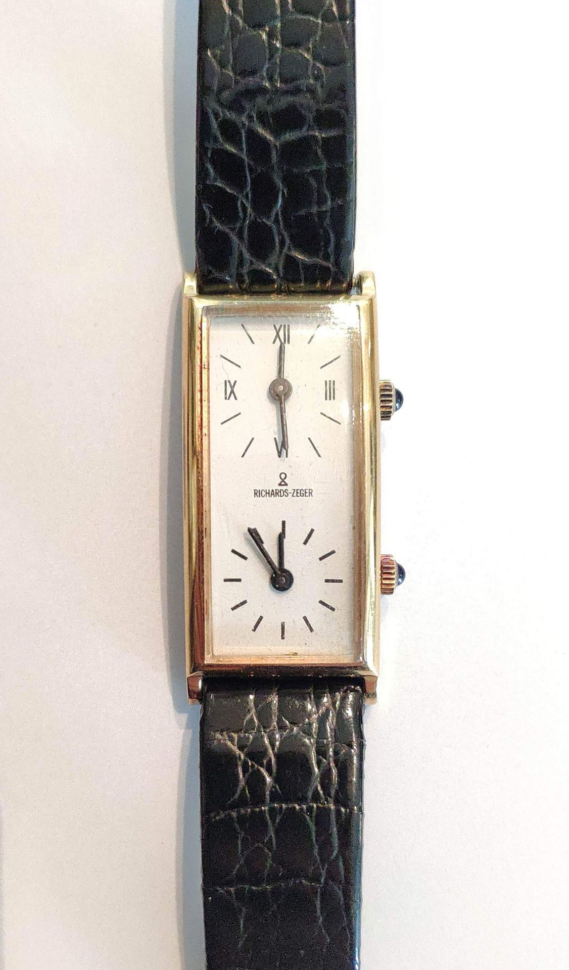 Null 里查德-泽格
腕式手表
黄金材质，白色背景的长方形表盘，两个提供双时区的表盘，两个凸圆形蓝宝石上链器，机械机芯，黑色皮表带配针扣。 
表盘的尺寸：18&hellip;
