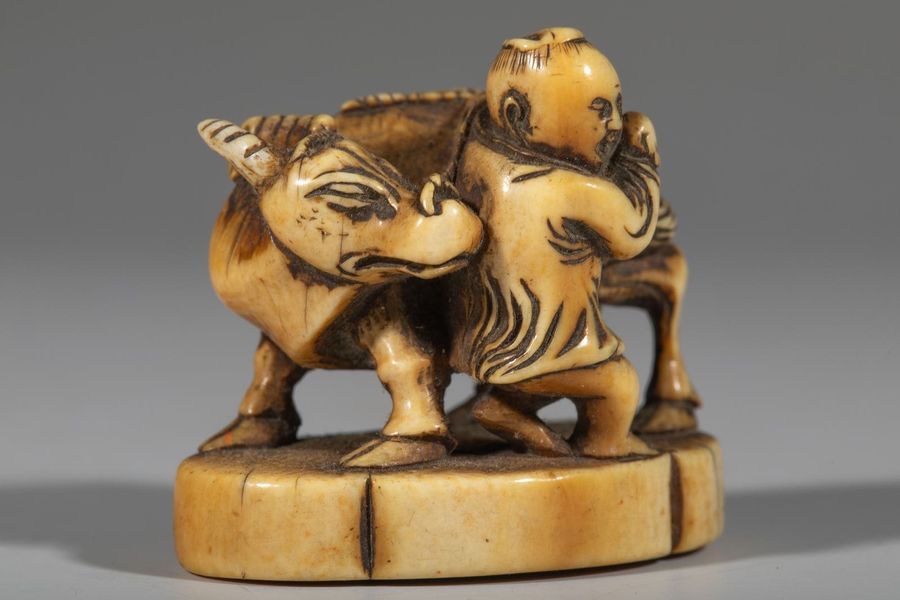 Null Okimono en ivoire, représentant un enfant tenant un buffle. H : 3,5 cm. Sig&hellip;