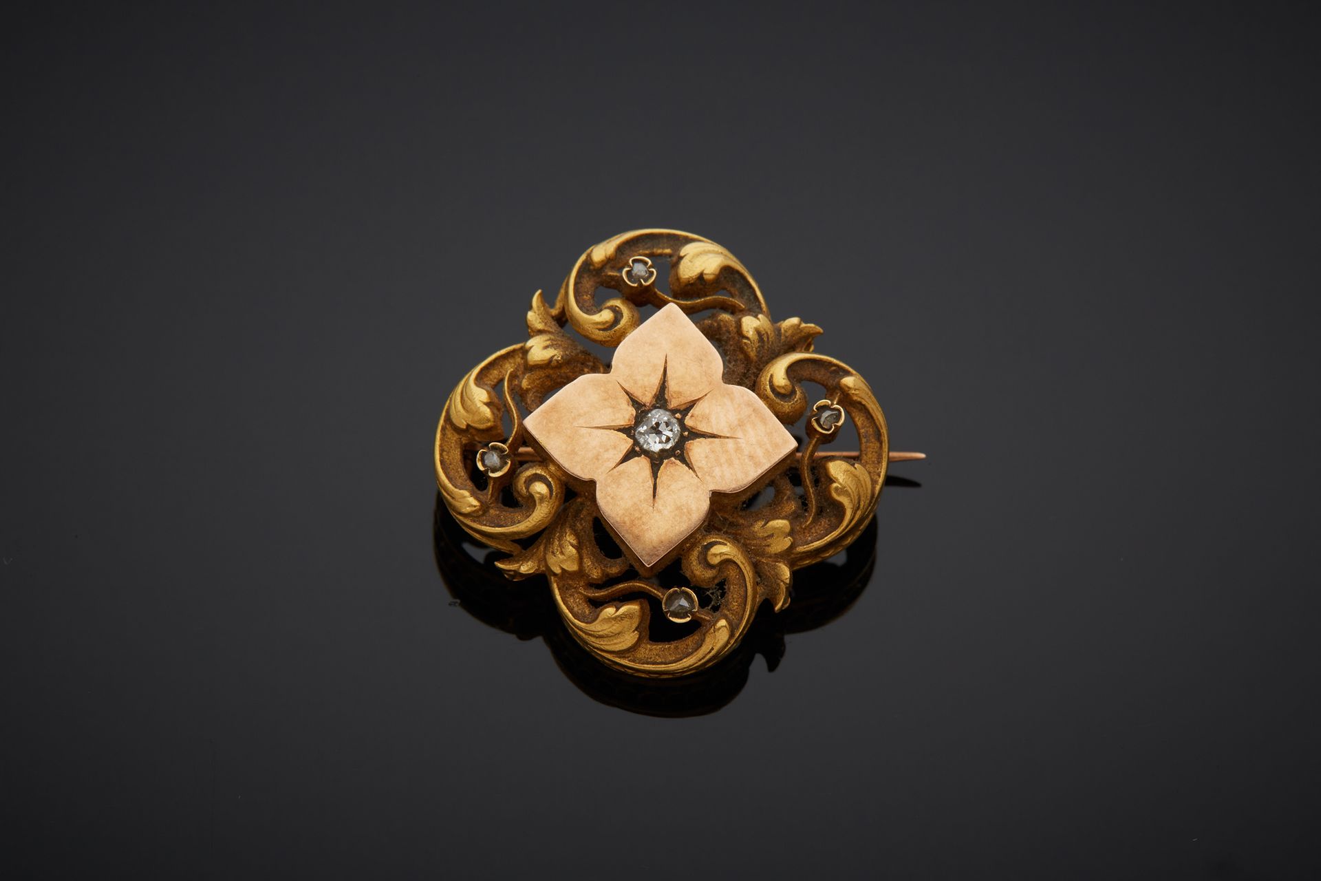 Null An 18K 750‰ two-tone gold brooch, four-lobed, chased with scrolls, centered&hellip;