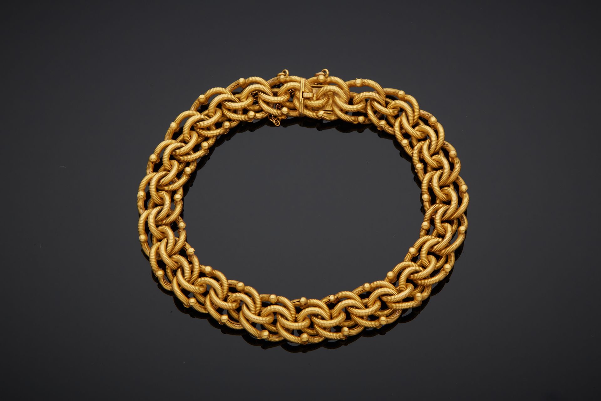 Null 750‰的18K黄金卷边，装饰有交错和条纹图案，带8和安全链的棘轮扣。

长18.50厘米 重量14.60克