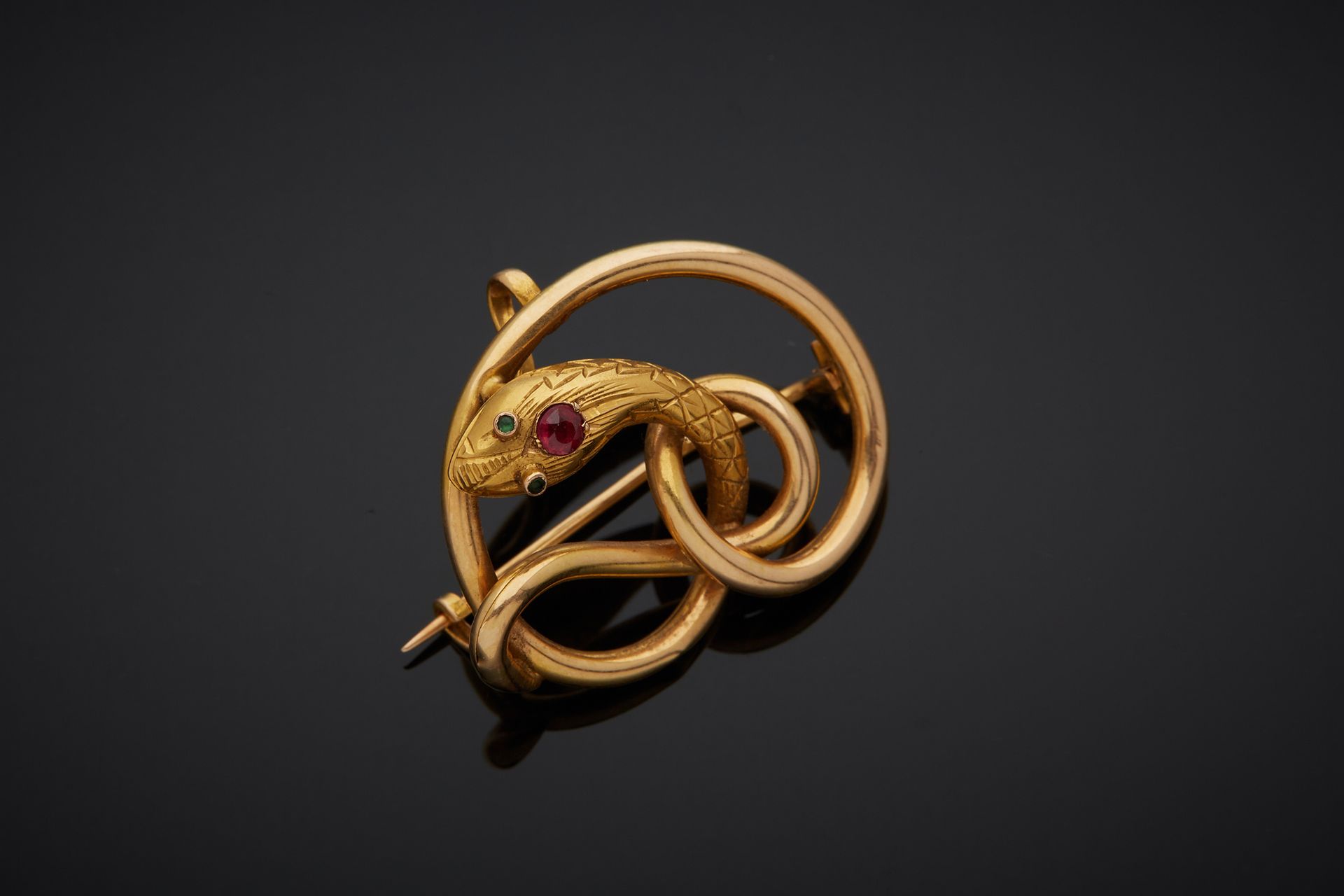 Null 一枚18K黄金750‰胸针，呈蛇形，头部装饰有红色宝石，眼睛有绿色宝石。配有一个挂钩。

尺寸：2×2.80厘米

毛重 : 2,70 g