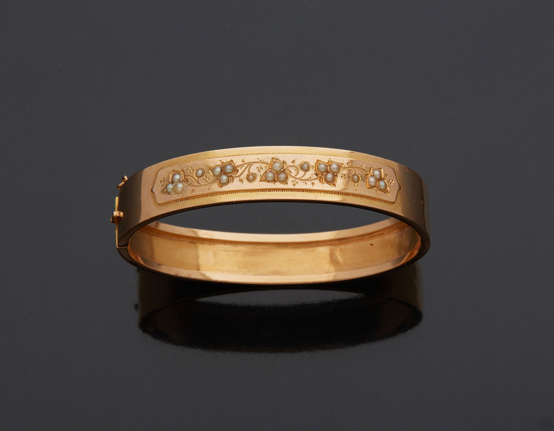 Null 18K黄金750‰的刚性手镯，装饰有雕刻的带子，镶嵌有半颗珍珠。

用铰链铰接，用带安全链的棘轮关闭。

内直径5.80厘米 毛重14.40克