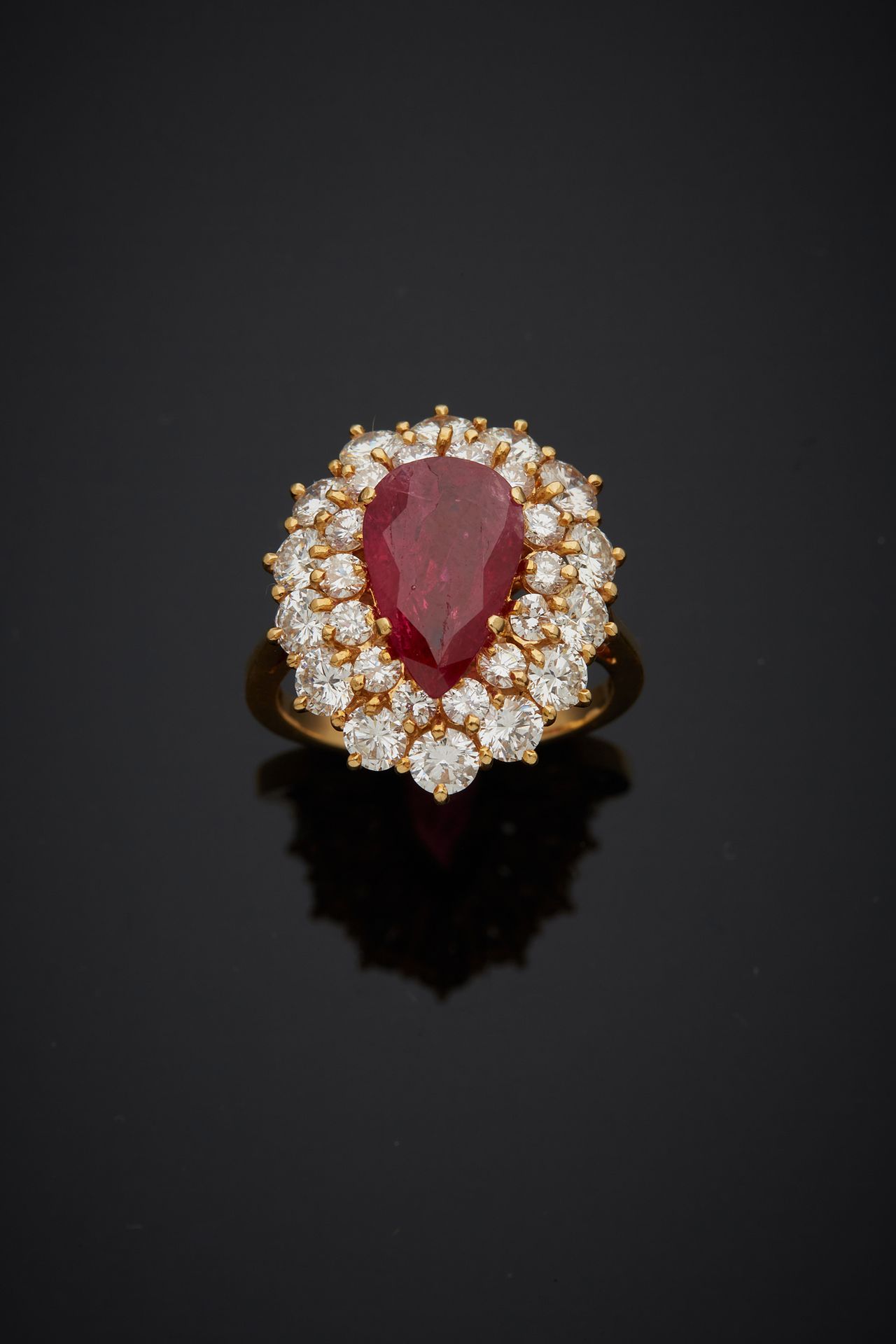 Null 一枚18K黄金750‰的戒指，镶嵌着一颗梨形红宝石，在双环明亮式切割钻石的包围下。

手指尺寸53 毛重6.80克