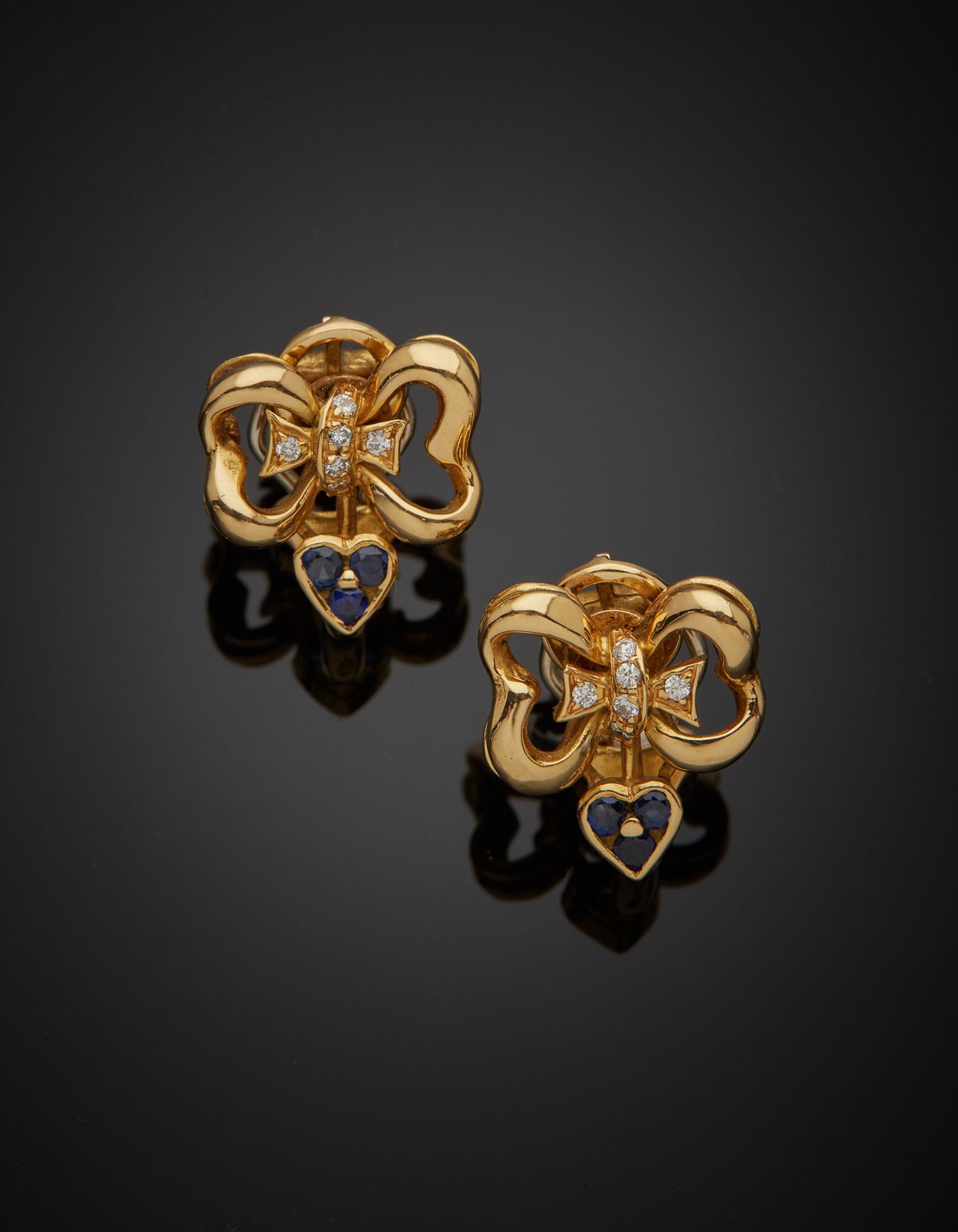 Null 一对双色18K金750‰的弓形耳夹，镶嵌着明亮式切割钻石和圆形蓝宝石。使用的痕迹。

H.1.80厘米 毛重11克