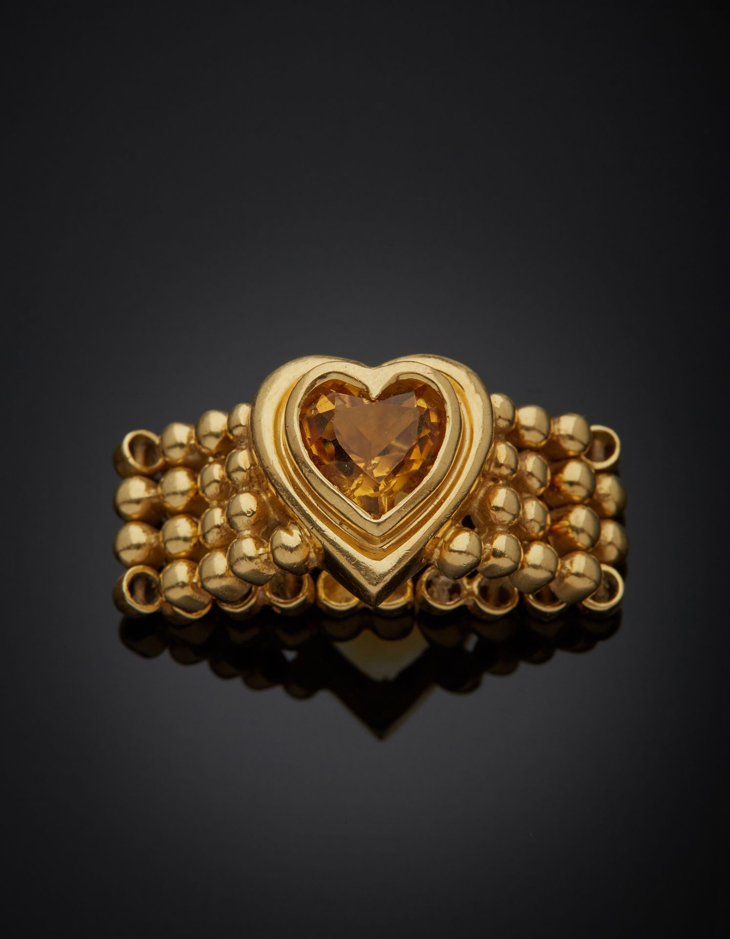 Null 一枚18K黄金750‰的戒指，镶嵌着心形设计的黄水晶，戒指由衔接的球状图案组成。有使用过的痕迹，有石块剥落。

手指大小54，毛重11.30克