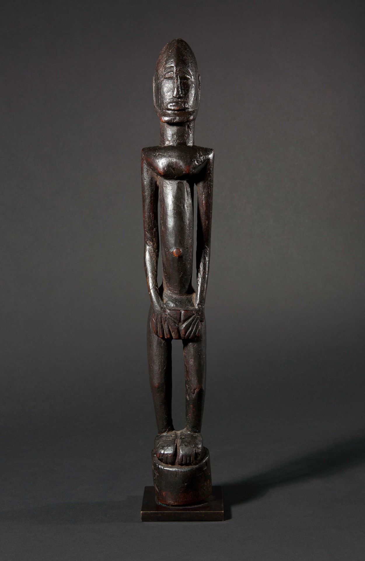 Null 雌雄同体的祖先的硬木雕像，有古老的棕色和红色铜锈，有些地方有光泽。他的双手放在下腹部，以示象征性的姿态。他站在一个圆形的基座上，他的脸有一个美丽的层次&hellip;
