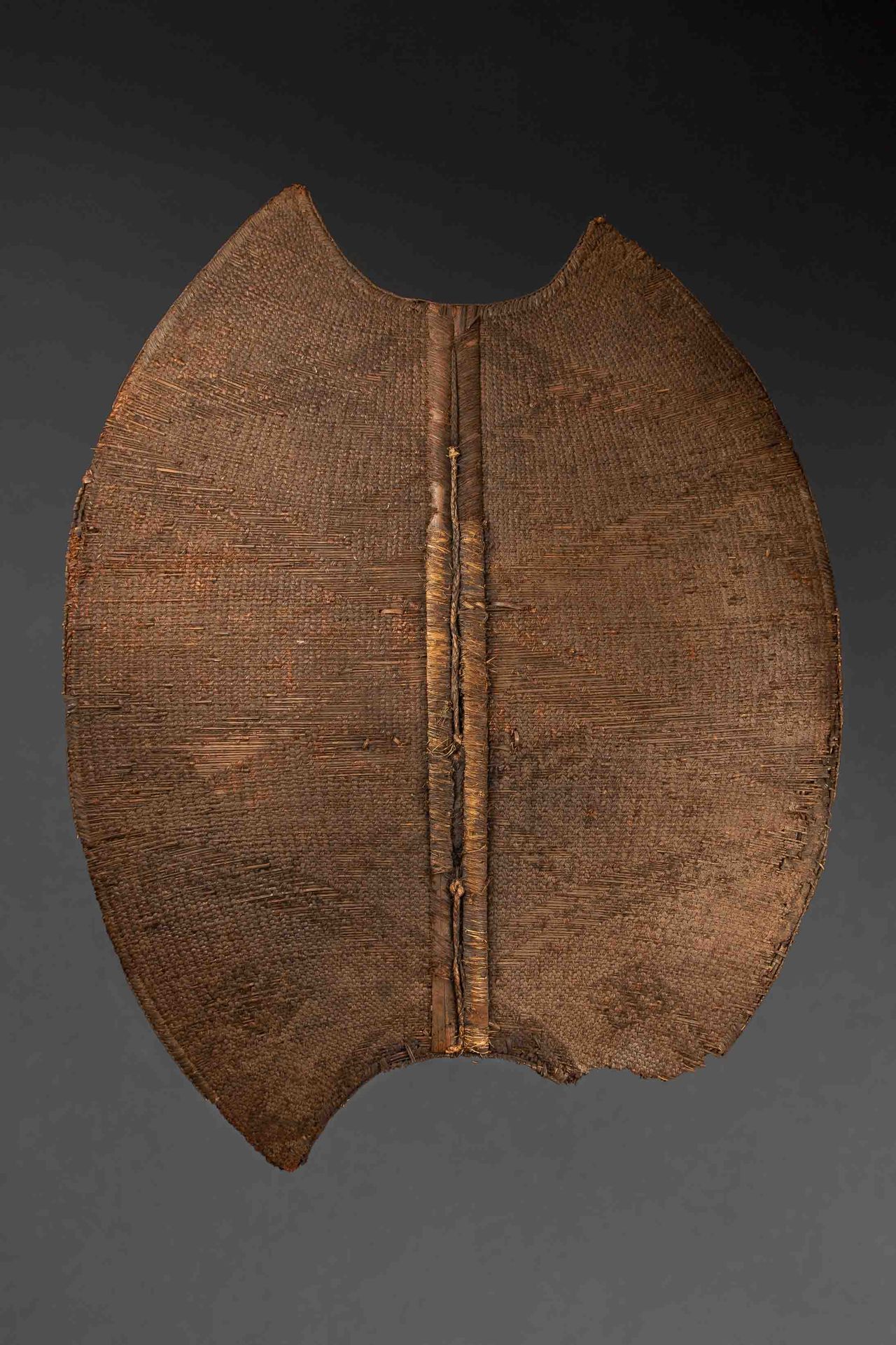 Null Kor盾牌有两根中心肋骨，木质框架上的编织篮子，有古老的光泽和使用的痕迹。喀麦隆曼比拉，20世纪。高度：119厘米