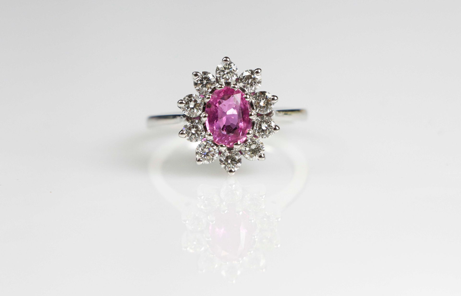 Null 一枚白金戒指，镶嵌着一颗1.5克拉的椭圆形切割粉色蓝宝石，并由总共约1克拉的钻石组成。毛重：7.1克