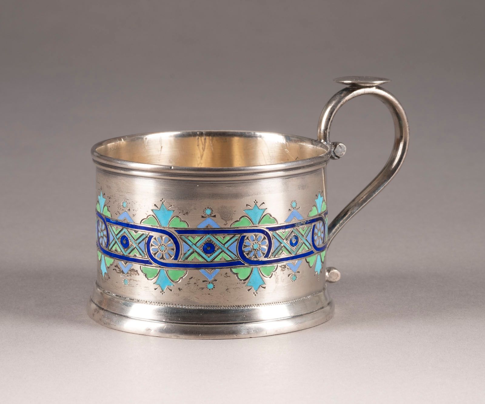 A SILVER AND CHAMPLEVÉ ENAMEL TEAGLASS HOLDER 
UN PORTATILE IN ARGENTO E SMALTO &hellip;