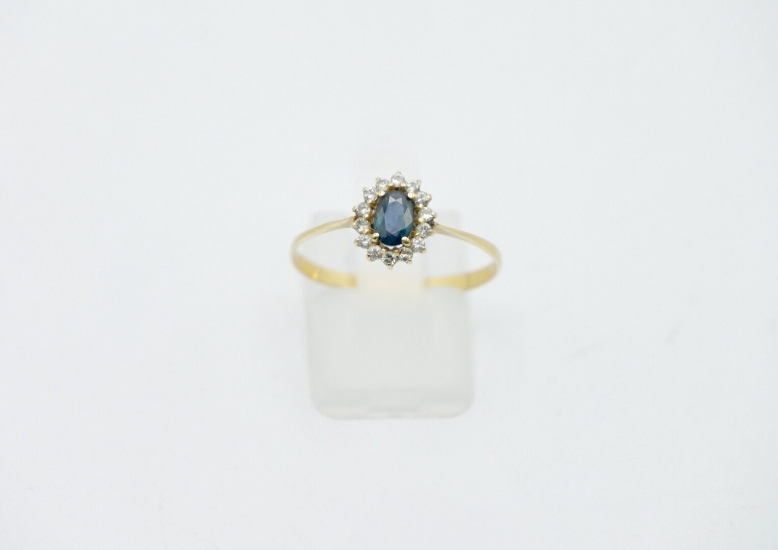 Null 750/1000e金戒指，中间是一颗蓝色宝石，周围是小钻石。

毛重：1,4克。

手指大小：58

对环的变形，使用状态