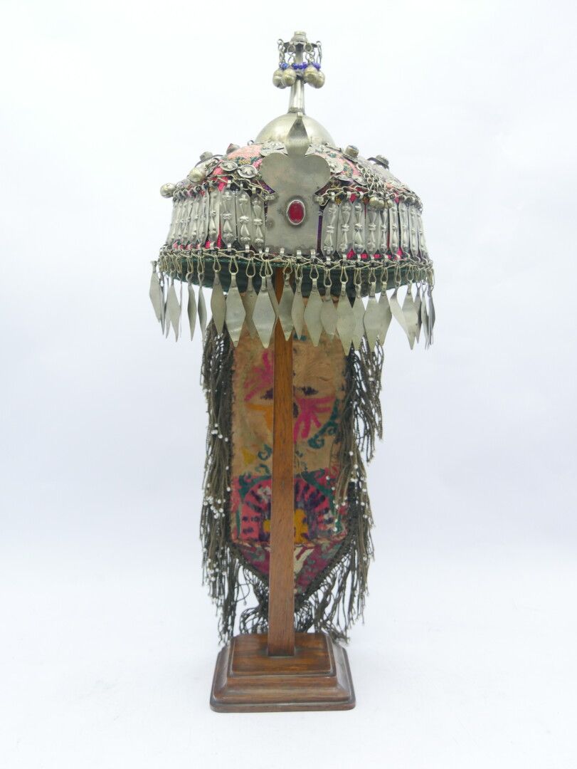 Null AFGHANISTAN - 20世纪初

金属和纺织品新娘头饰，装饰有饰物、铃铛、珠子和吊坠

木质底座

H.50厘米。19 3/5英寸。

金属变&hellip;