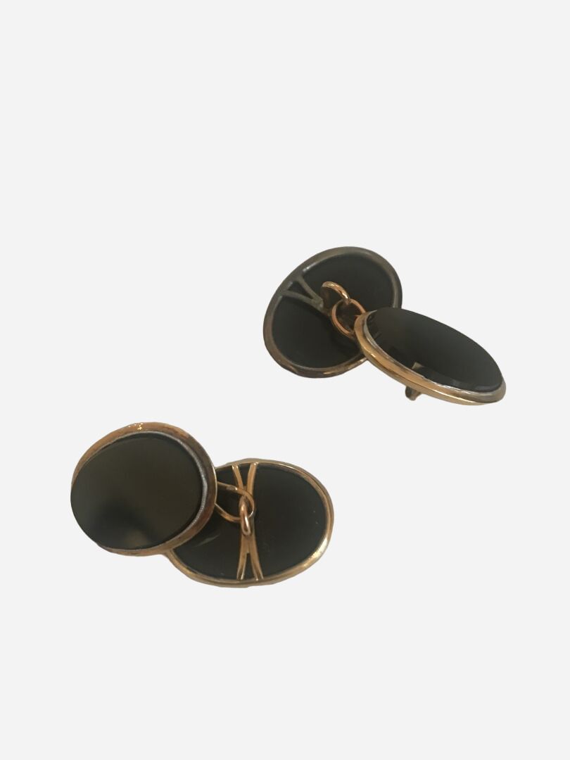 Null 20世纪初 
袖扣一对，椭圆型金质镶嵌黑色玻璃奖章
毛重：12.1克。 

划痕，使用状态 

盒子里有一个顶着珍珠的大头针。