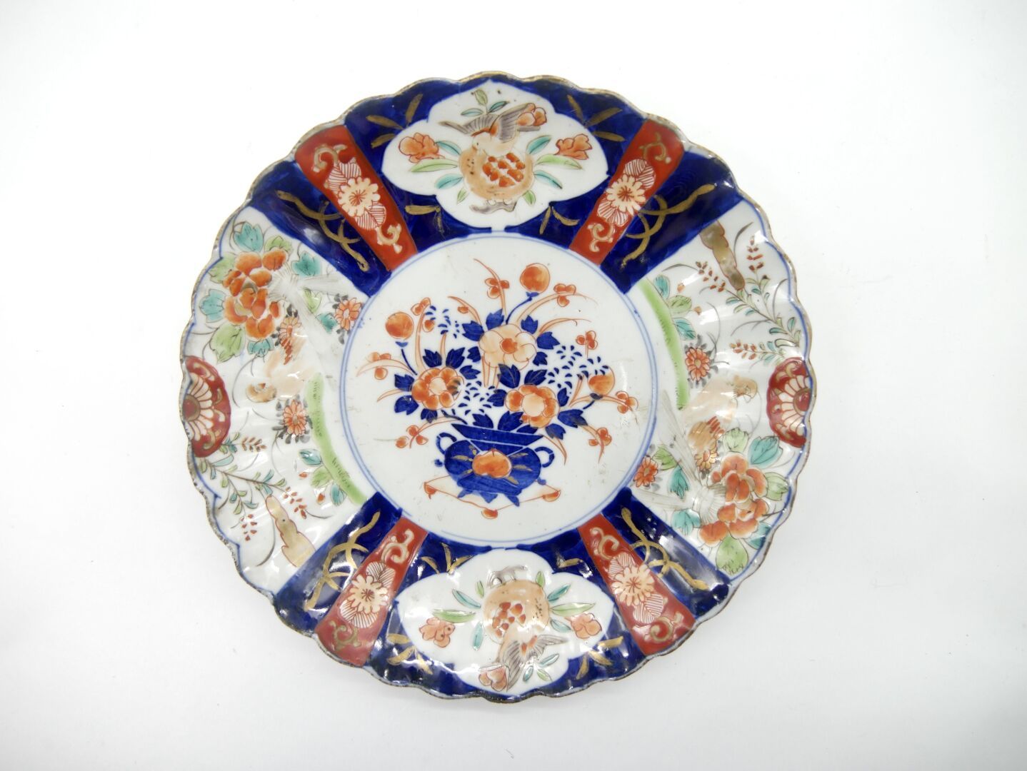Null 日本，伊万里 - 20世纪初
被称为 "伊万里 "的铁红和金色珐琅蓝釉瓷盘，中央饰有显示花瓶的奖章，两翼饰有相同的花朵和羊齿纹 
直径：21.5厘米，&hellip;