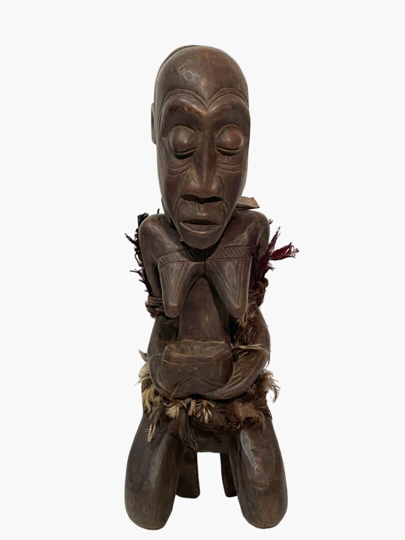 Null 非洲 
大型拜物教式雕像 
跪着的女性形象，拿着一个杯子
带有深棕色铜锈的木头，羽毛，纤维
H.57 cm. 22.50 in.