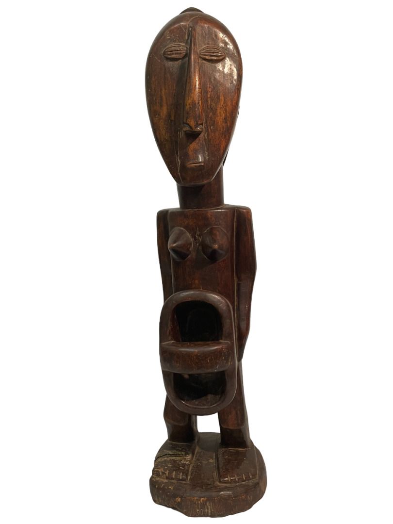 Null 非洲 
部落灵感的雕像
腹部被掏空，头饰上有一连串的圆圈。
木质，有棕色至黑色铜锈
H.67 cm. 26.40 in.