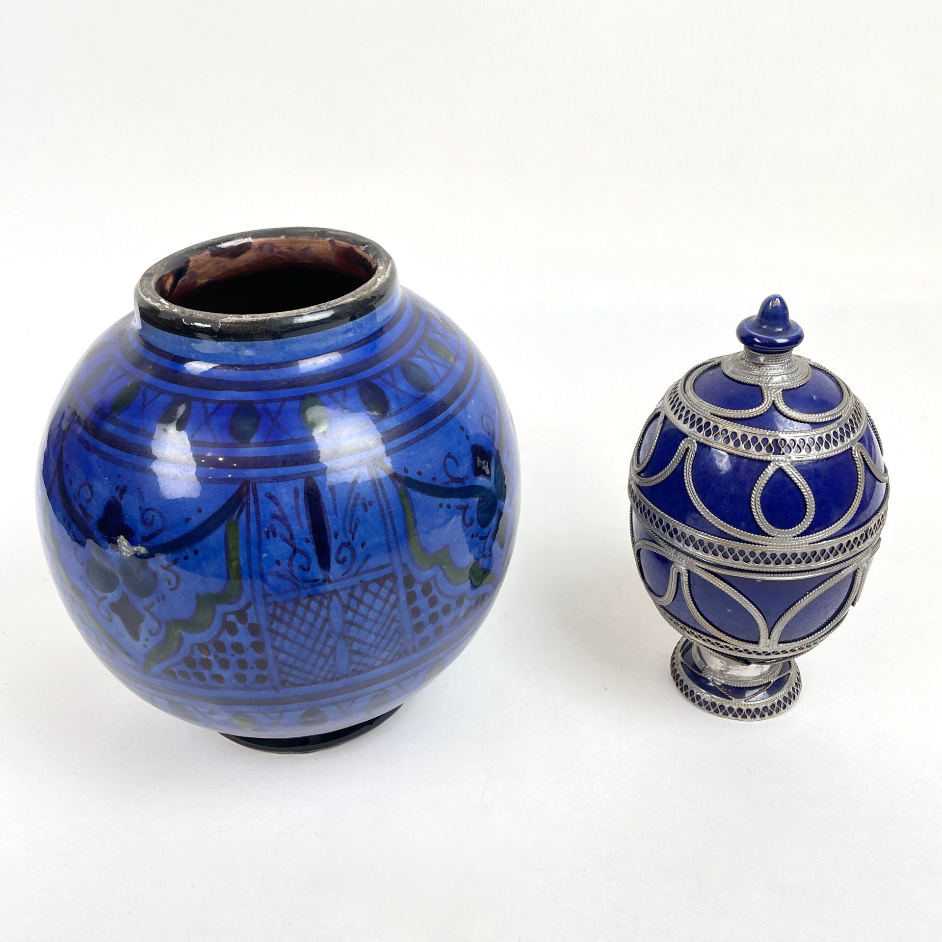 Null 北非 
一套两件蓝釉陶瓷器： 
- 球形花瓶，黑色植物装饰。尺寸：约 20 x 20 厘米 
- 带镂空金属框的蛋形盒子。高度：19.5 厘米。 

&hellip;