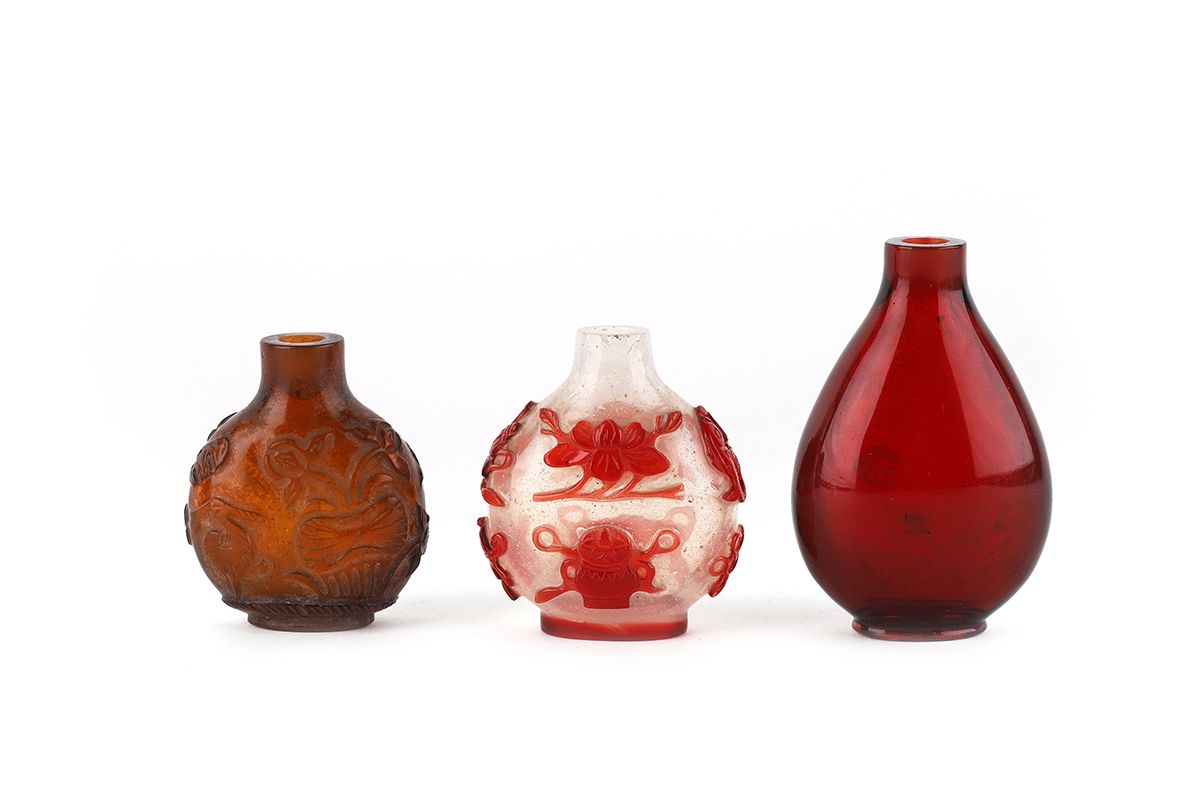 Null 中国，19世纪

一套三个玻璃鼻烟盒，其中一个是在半透明的背景上覆盖红色，装饰有八个佛教符号。塞子不见了，颈部有一个小缺口。棕色玻璃鼻烟壶，有浅浮雕的&hellip;