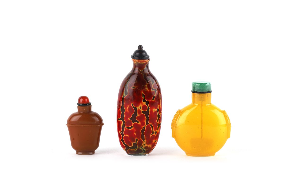 Null 中国，19世纪

一套三个玻璃鼻烟盒，其中一个是仿雄黄的橙红色调，木塞。第二件是半透明的黄色玻璃，两边是狮子面具形状的把手，玉石塞。第三件在不透明的焦&hellip;