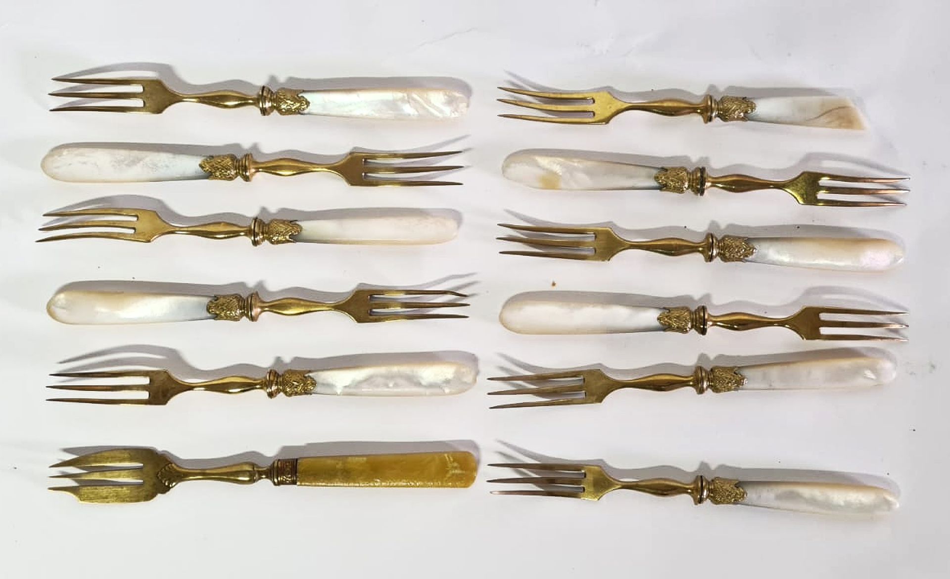 Null 鎏金金属和珍珠母手柄的水果服务套装，包括:

11个叉子

12把刀

(对珍珠母的意外)

一把镀金金属和树脂手柄的蛋糕叉子