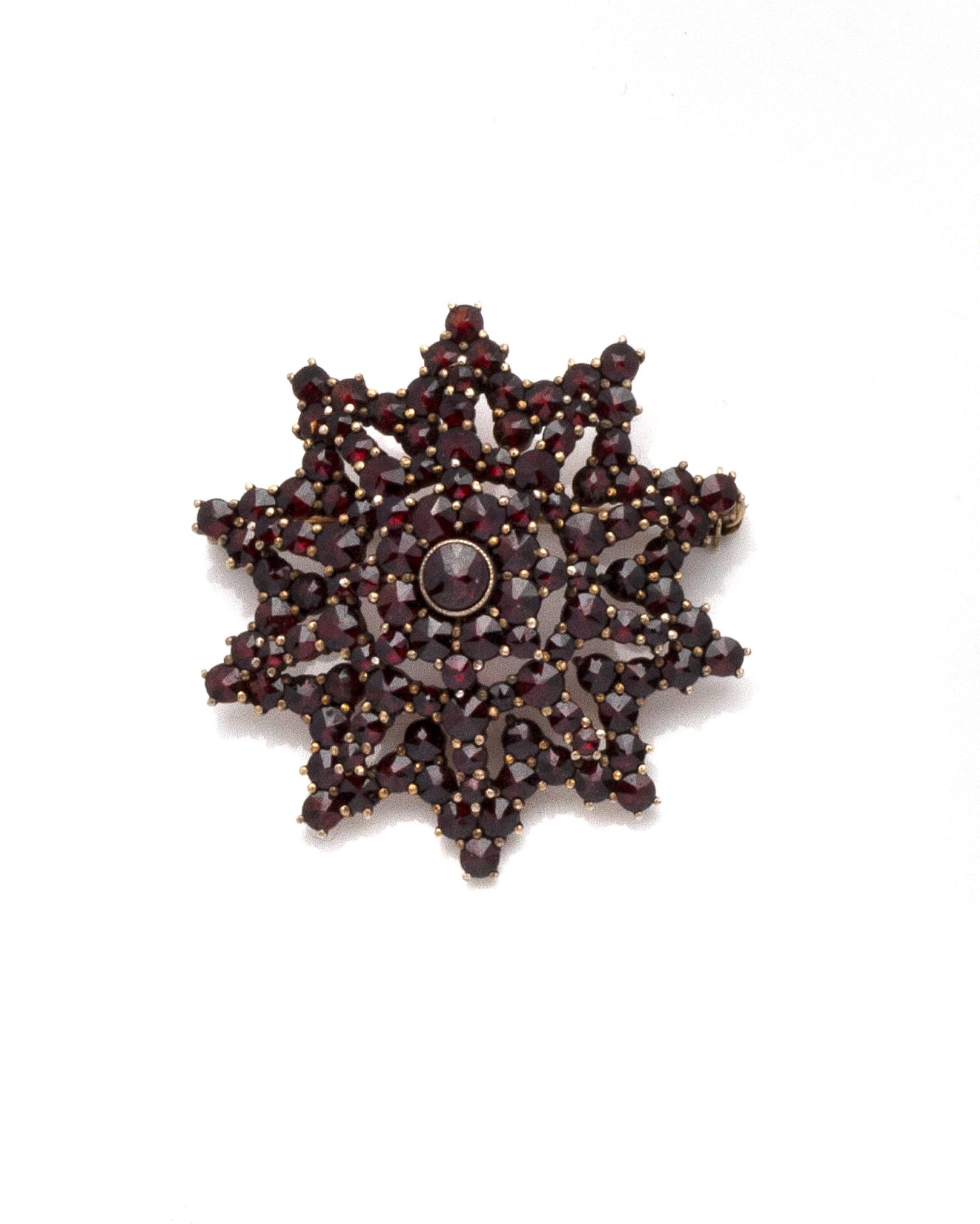 Null 一枚代表双十角星的镀金胸针，镶嵌着佩皮尼昂石榴石。有安全保障的针。

西班牙，19世纪（加泰罗尼亚印记）

直径：4厘米 - 总重量：10.91克