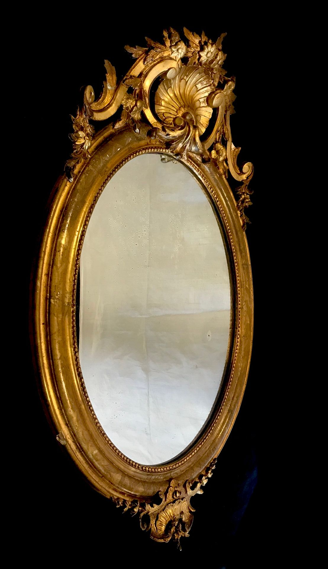 Null 
木制和镀金灰泥的大型椭圆形镜子。上面有一个丰富的路易十五风格的外壳。拿破仑三世时期，19世纪末。高92厘米。宽度为50厘米。小事故。
