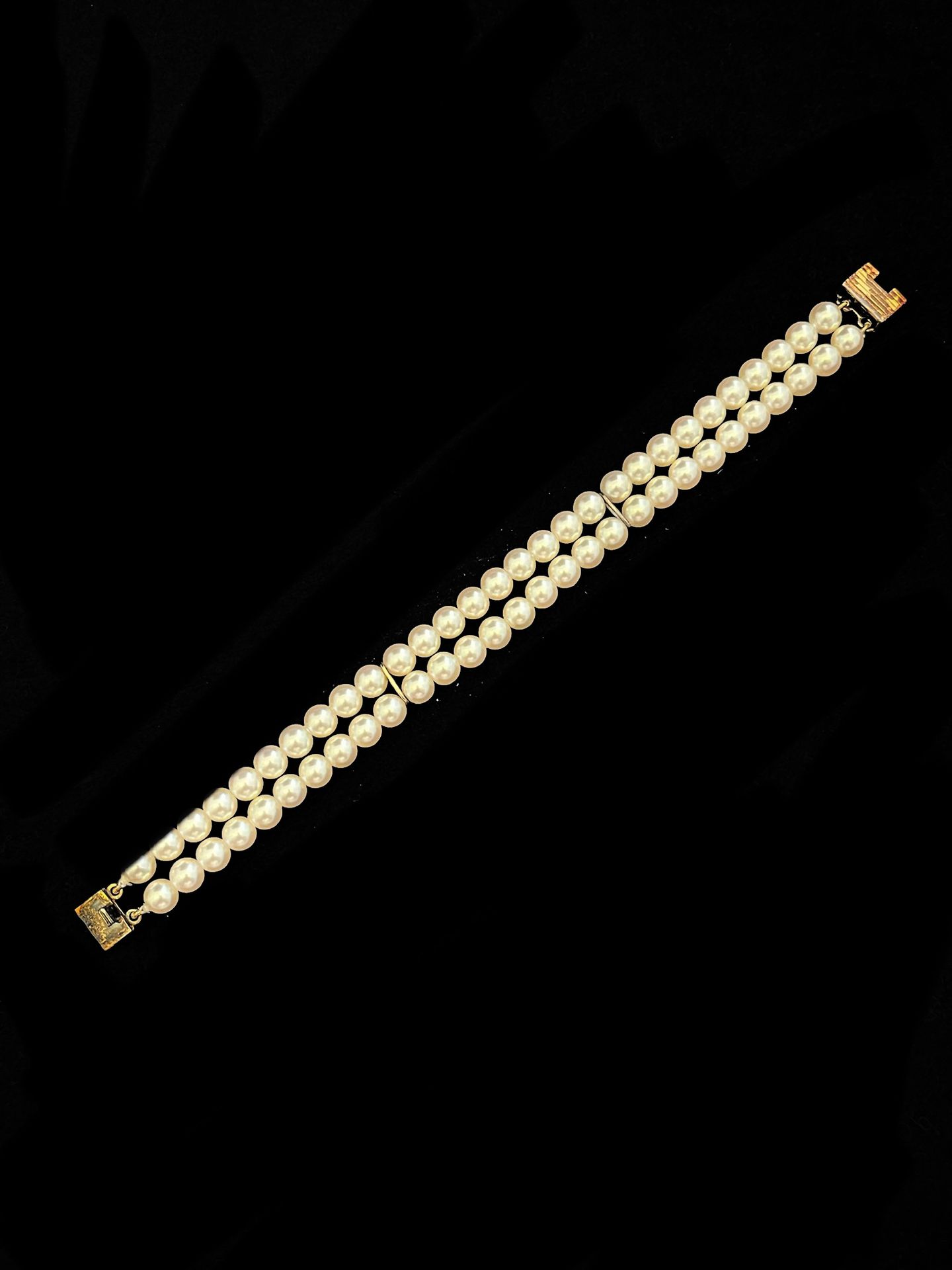 Null 手链上有两排梦幻般的珍珠，由镀金的金属条点缀。镀金表扣。