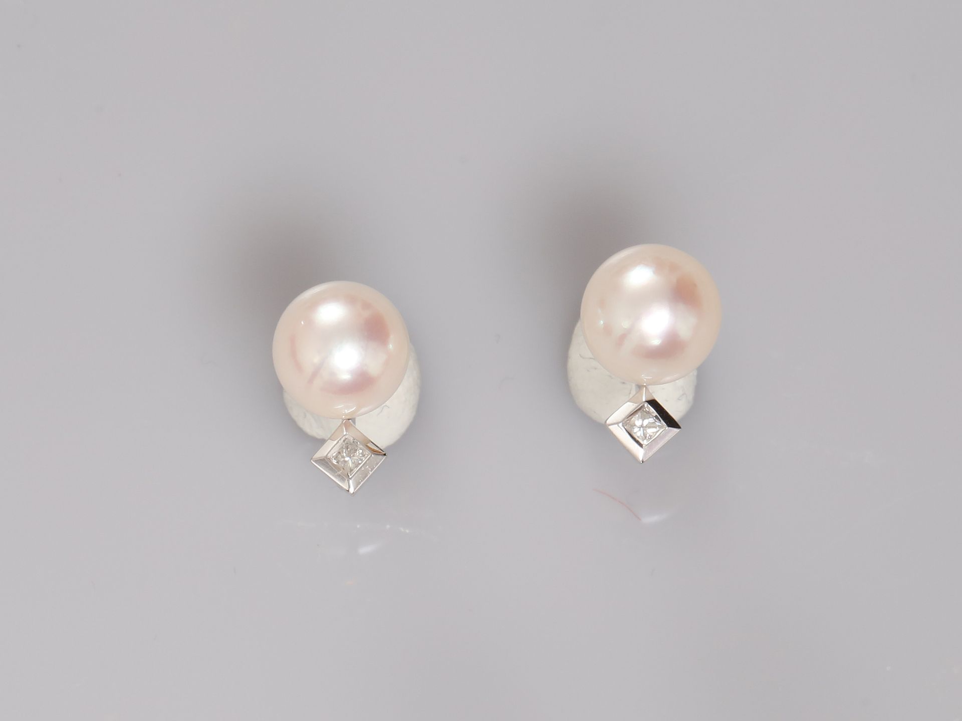 Null 白金耳环，750毫米，每只都镶嵌有一颗直径为7.5/8毫米的日本养殖珍珠，冠以一颗钻石，重量：2.4克。