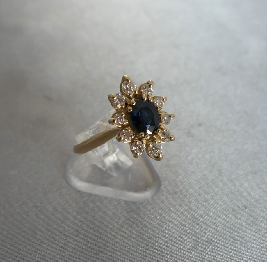 Null 750千分之一黄金戒指，镶有一颗约0.85克拉的椭圆形蓝宝石，周围有10颗钻石。毛重4,42克 - 尺寸53。专家：Béatrice MAISONNE&hellip;