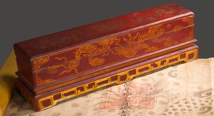 Null 红金漆木质御用漆箱，饰有云中凤凰和吉祥物。顺化，19世纪下半叶。高14.5厘米。长度：50.5厘米。深度：13厘米。(损坏和丢失的部件）。)