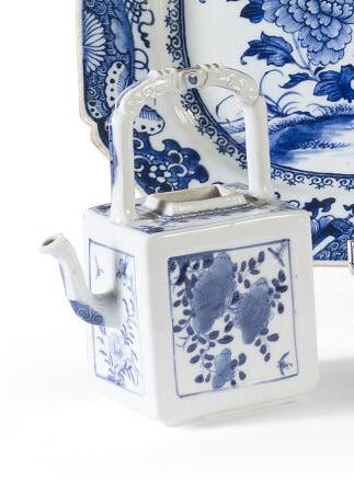 Null 一个白色和蓝色的珐琅彩茶壶，方形，上部有一个宽大的把手，装饰有蝴蝶和花叶的奖章。底座下有叶子标记。中国，康熙年间。

高度：16.5厘米。