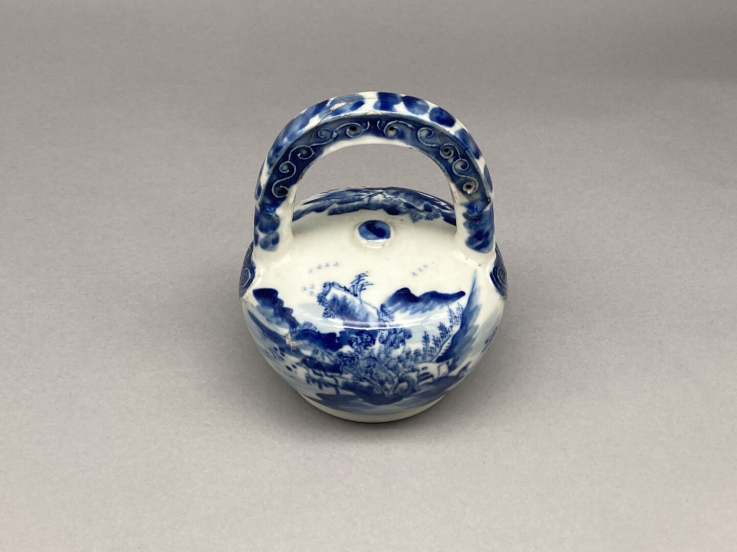 Null 青花瓷石灰壶，名为 "Hue blue"，装饰有生动的湖泊景观。

印度支那，19世纪末和20世纪初。

高度：14厘米。

(事故和修复）。