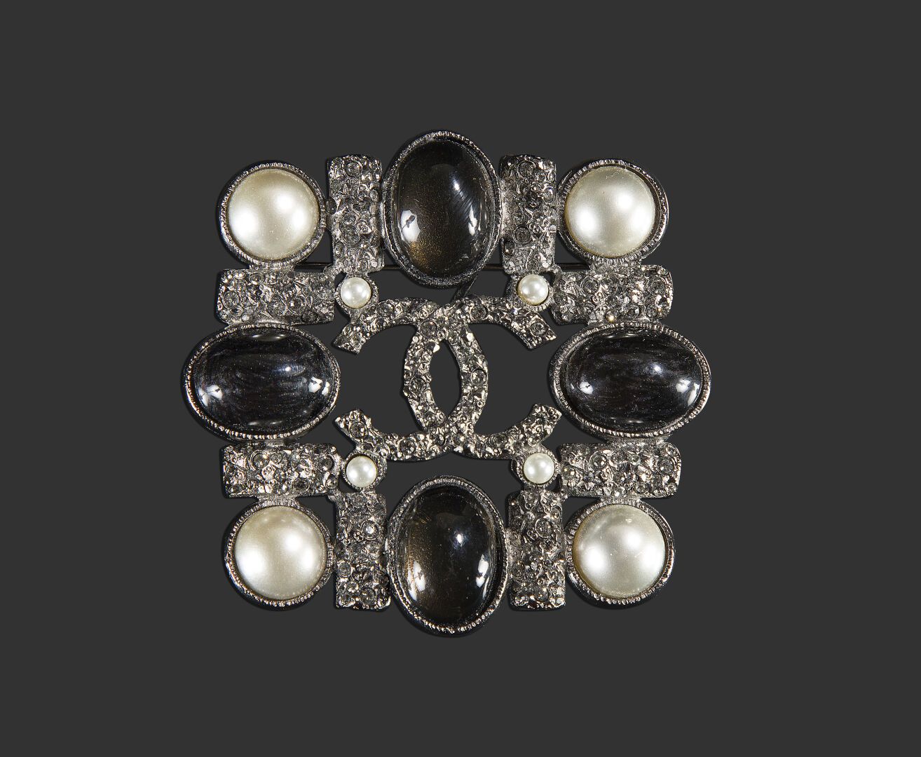 Null 香奈儿

镀银金属方形胸针。装饰有一个标志和镶嵌的水钻、珍珠和五彩斑斓的黑色凸圆形玻璃。签名。

尺寸：7 x 7 cm