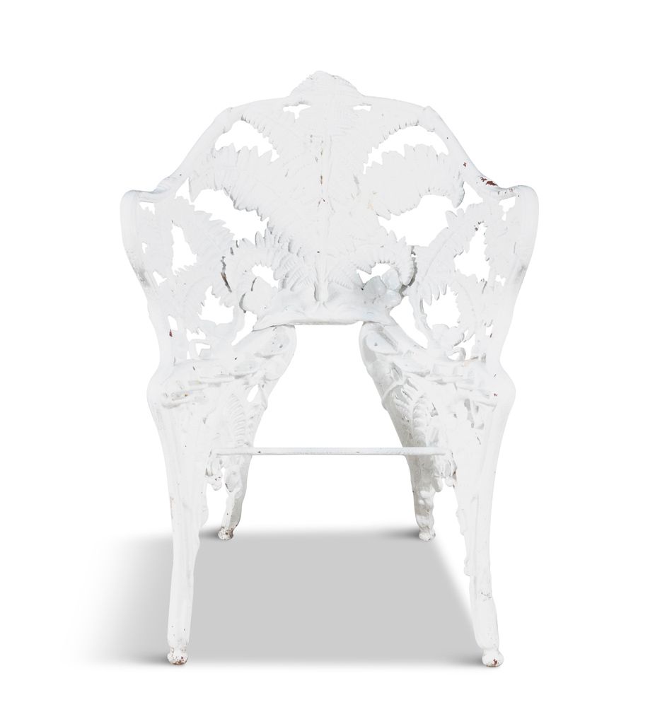 Null 一张维多利亚时期的铁制花园座椅，背上有穿孔，装饰着散落的蕨类叶子，腿部弯曲。