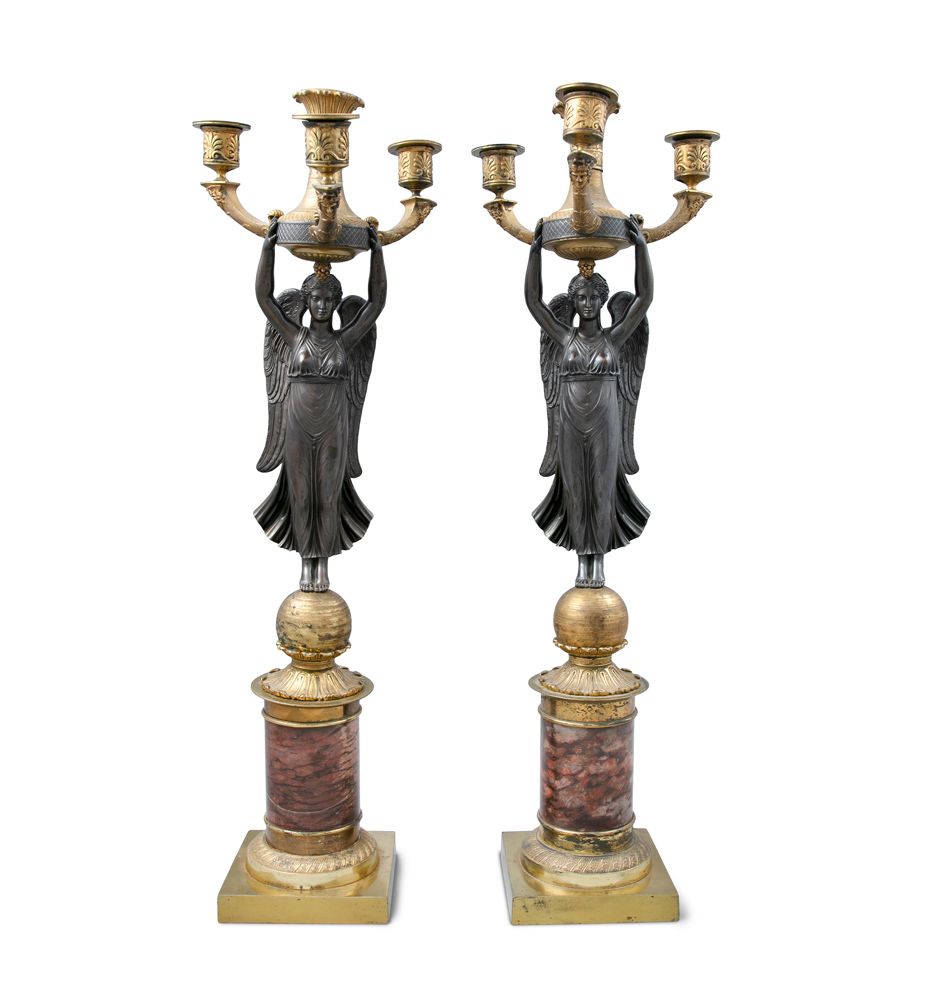Null 一对法国帝国奥莫卢和大理石雕像烛台，造型是一个带翅膀的胜利者，高举一个四光的火炬，平衡在一个球形和胭脂红的大理石柱上，放在奥莫卢基座上。高67厘米