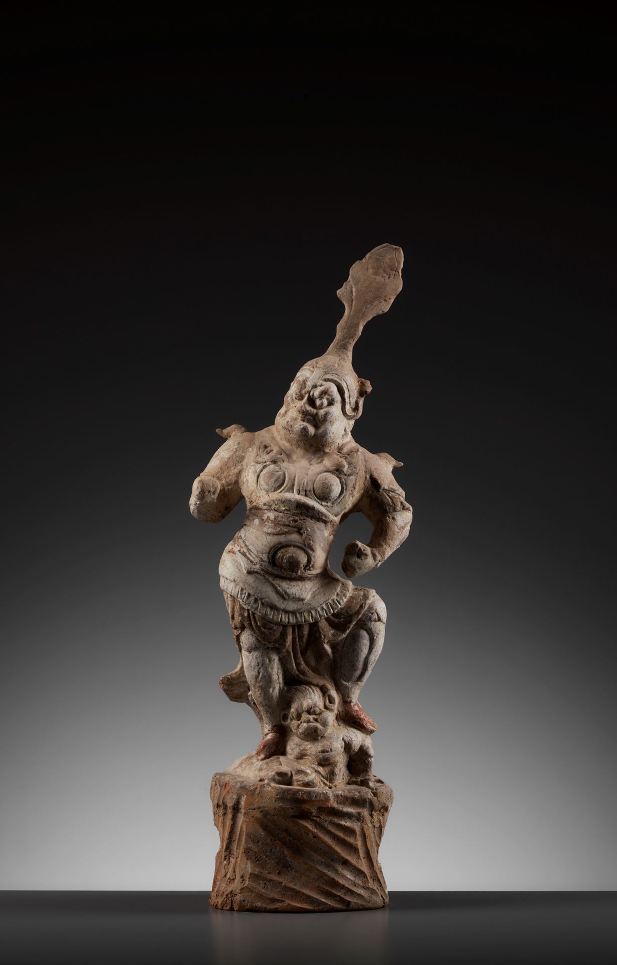 唐代彩绘陶俑中国，618-907。这个好战的人物胜利地站在一个躺在岩石基 