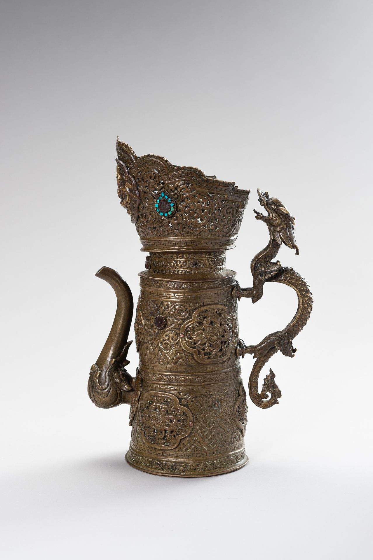 A BRASS REPOUSSÉ BEER EWER 一件铜制回纹啤酒杯
西藏，19世纪末。圆柱形的器身从平底上升到部分网状的冠部，都是用回纹精细地完成的。在卷&hellip;