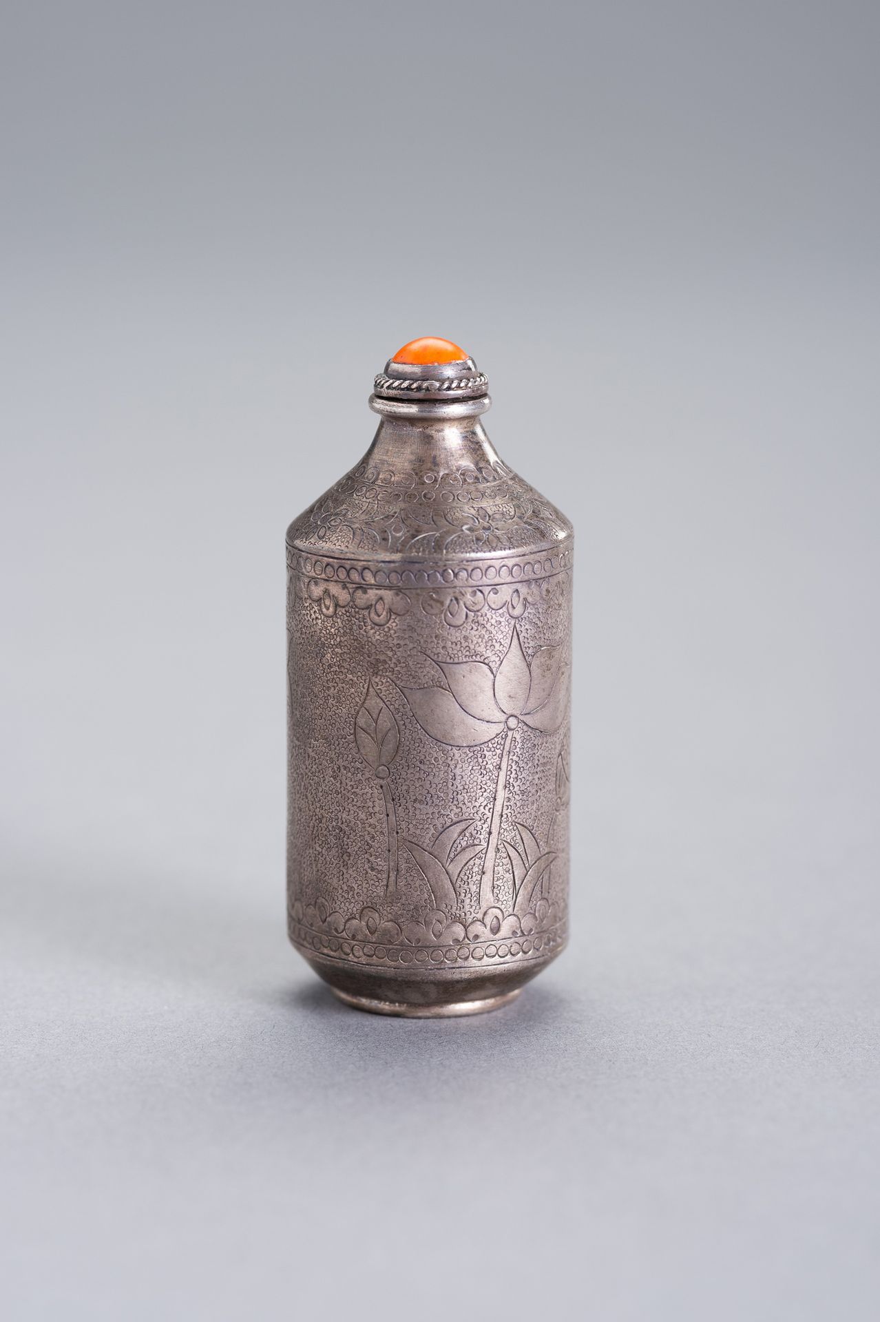 AN INCISED SILVER SNUFF BOTTLE 一个刻印的银质鼻烟壶
中国，19世纪。壶身细微地刻有荷花图案。底部印有两个纯银的印记。

状况良好&hellip;