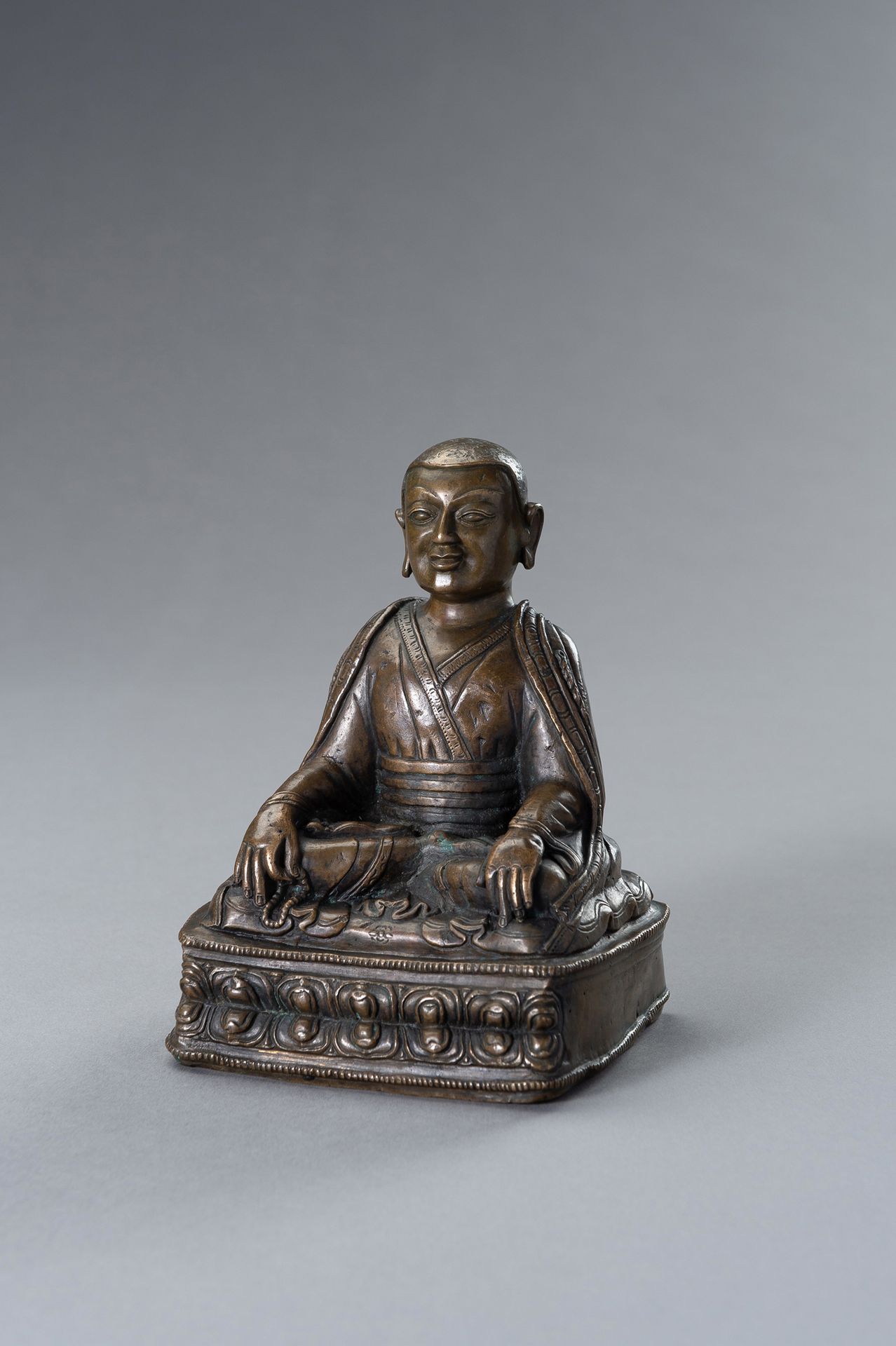 A Bronze figure of a Lama 喇嘛铜像
西藏，17至18世纪。坐在有珠边的双莲花座上，右手拿着祈祷珠，身穿飘逸的袍子。慈祥的脸，嘴唇抿成微&hellip;