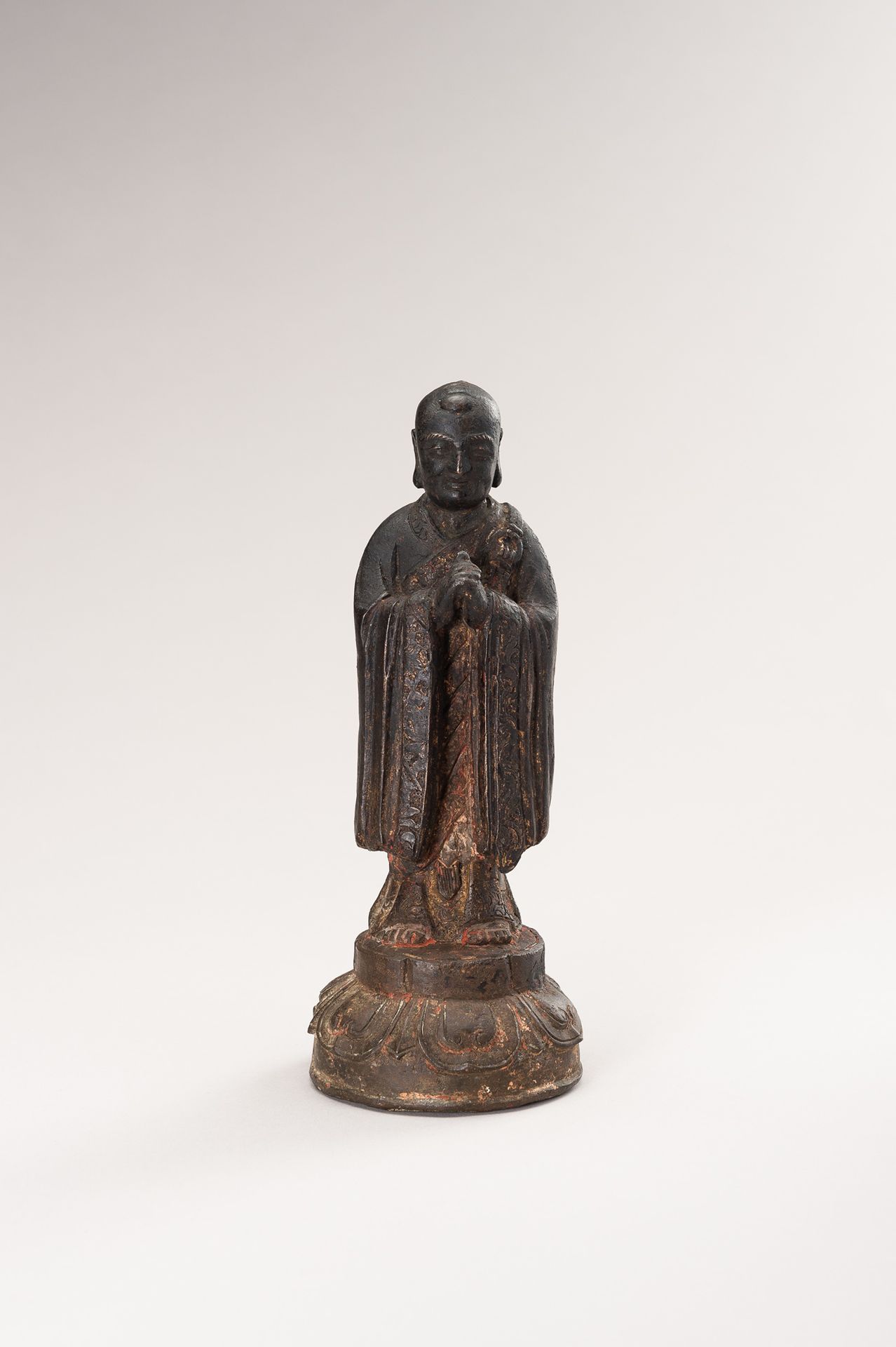 A BRONZE FIGURE OF A LUOHAN 罗汉青铜像
中国，明朝（1368-1644）。站在一个莲花底座上，双手合十放在胸前。飘逸的长袍下摆刻有叶&hellip;