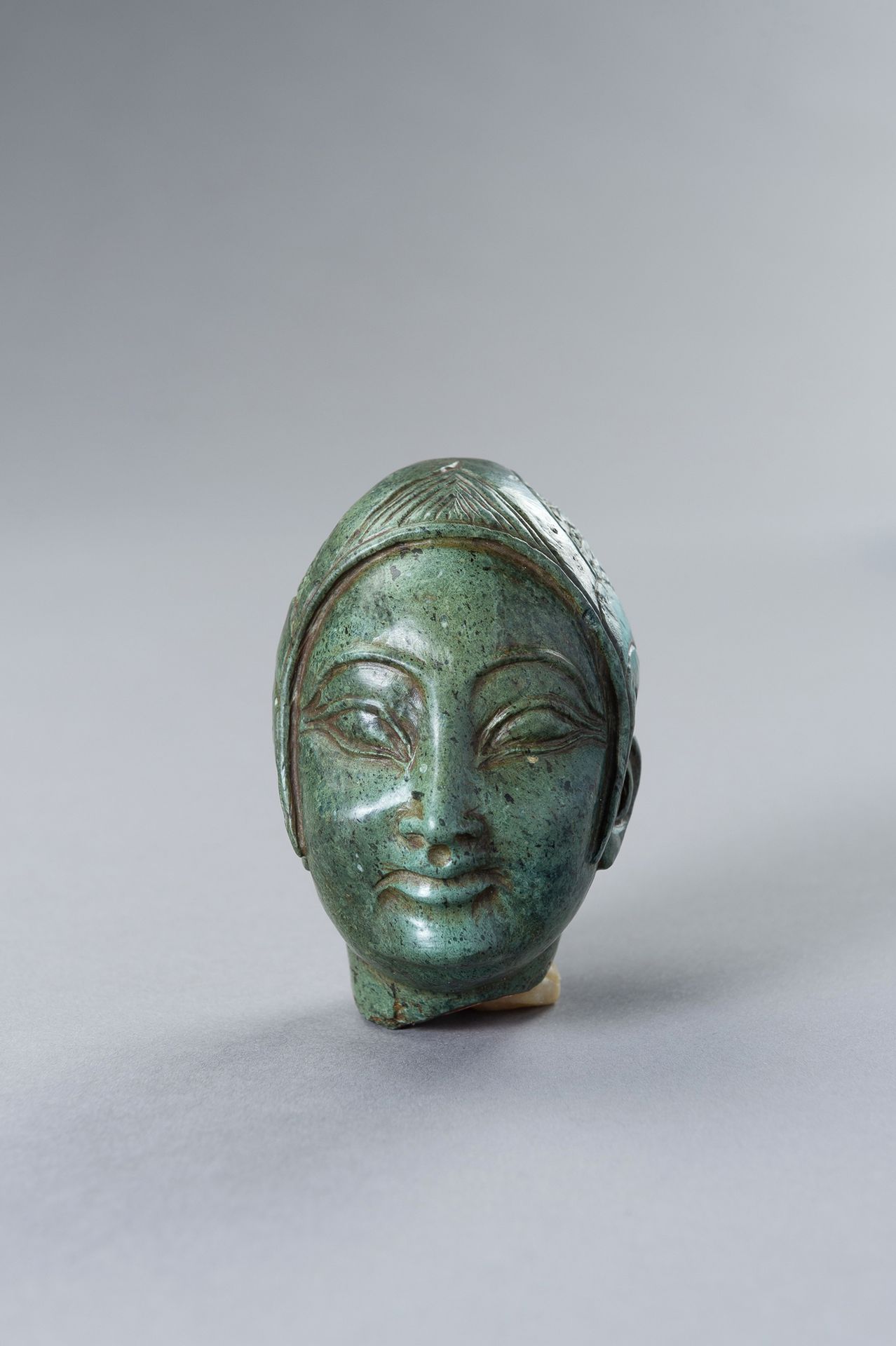 A GREEN STONE HEAD OF A FEMALE DEITY 绿色石雕女神头像
推测是中国，20世纪上半叶。女神穿着不寻常的鸟头服，石头是绿色的，有&hellip;